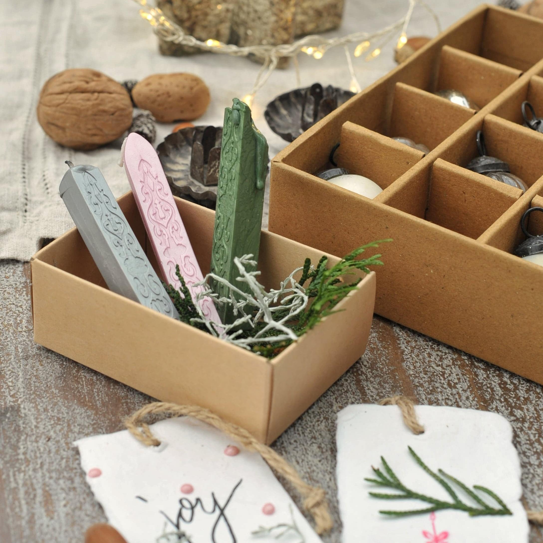 Drei bunte Siegellack-Stangen in Schachtel mit Naturdeko auf Holztisch für Geschenkverpackung