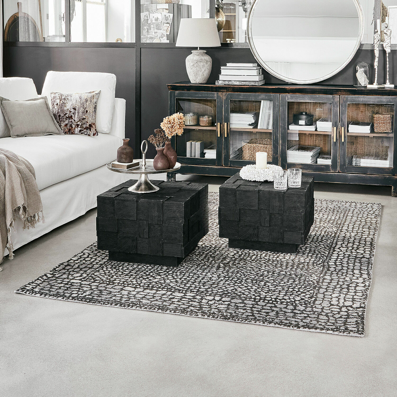 Teppich Vermont Zwei schwarze Holzcouchtische auf gemustertem Teppich in modernem Wohnzimmer mit weißem Sofa