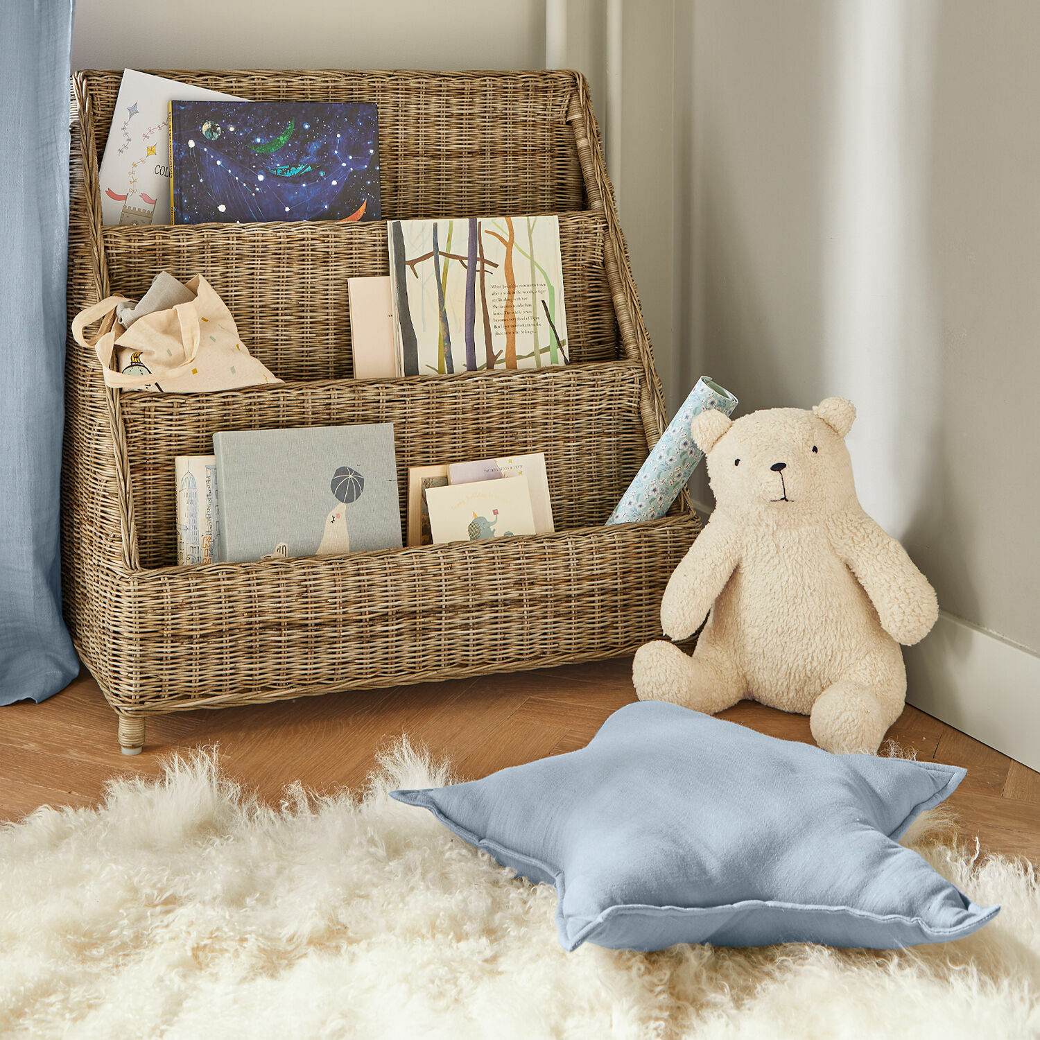 Natürlicher Rattan-Bücherregal mit bunten Büchern und Plüschbär im Kinderzimmer