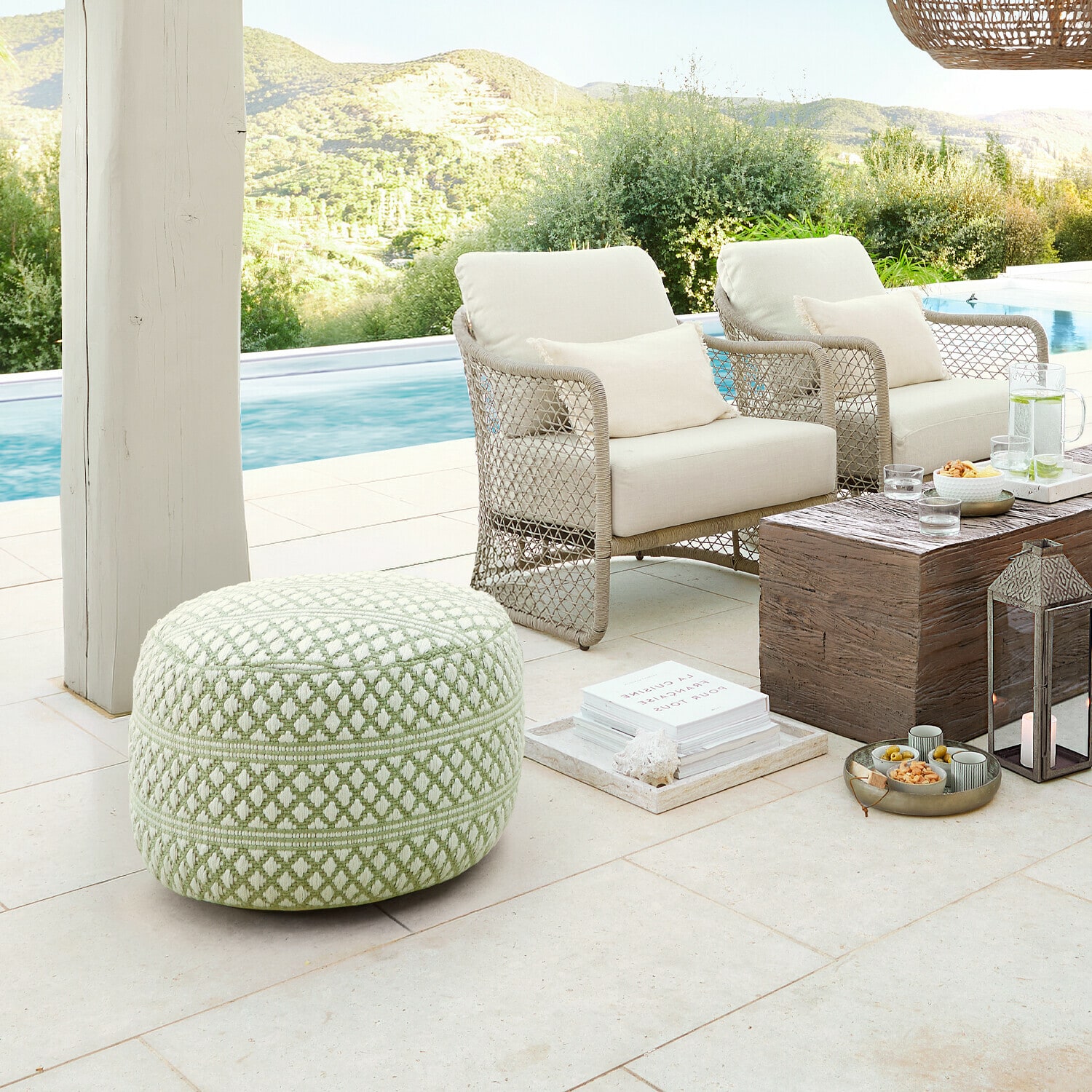 Weicher grün-weißer Stoff-Pouf mit geometrischem Muster auf Terrasse am Pool