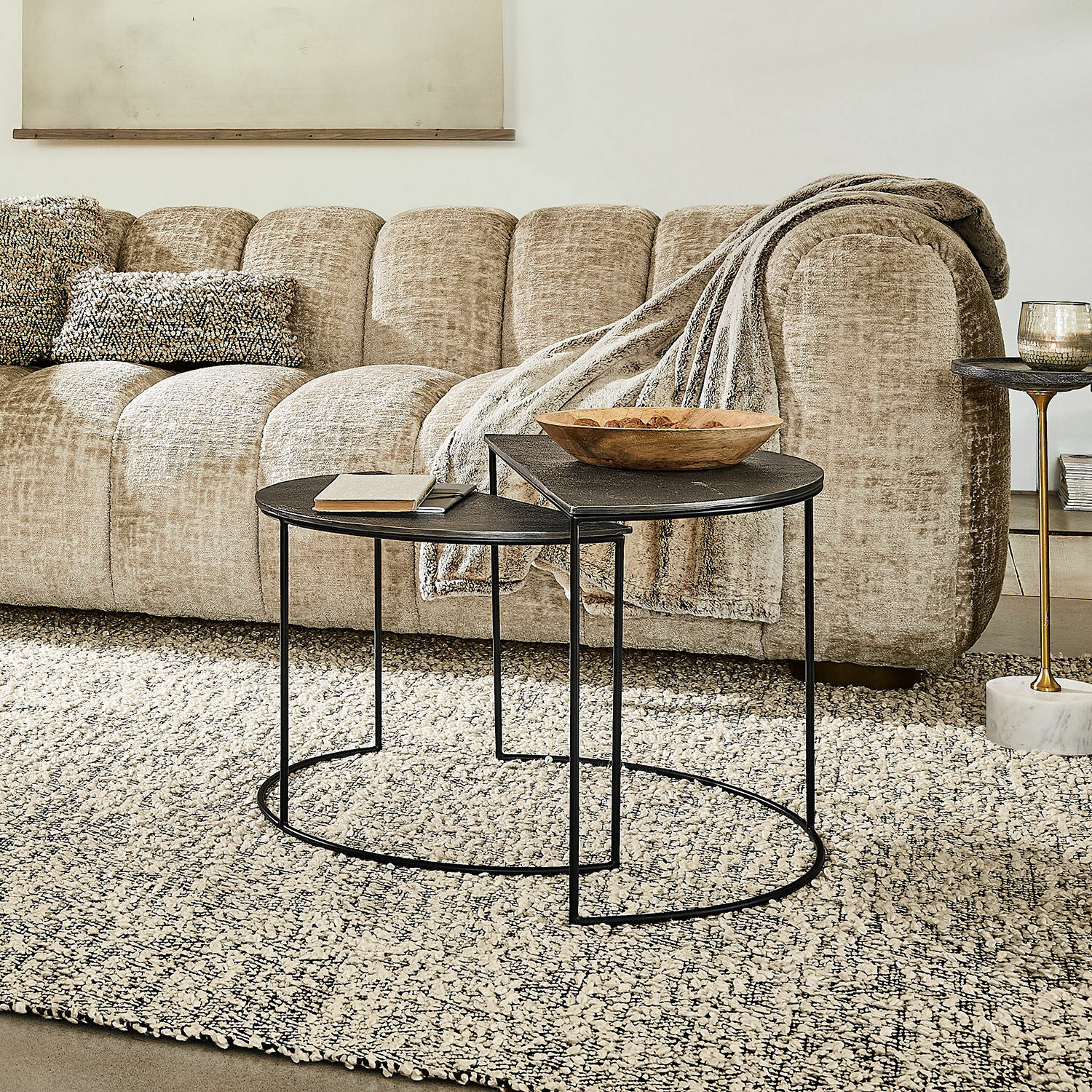 Zwei schwarze Metall-Couchtische mit runden Platten auf hellem Teppich vor beigem Sofa