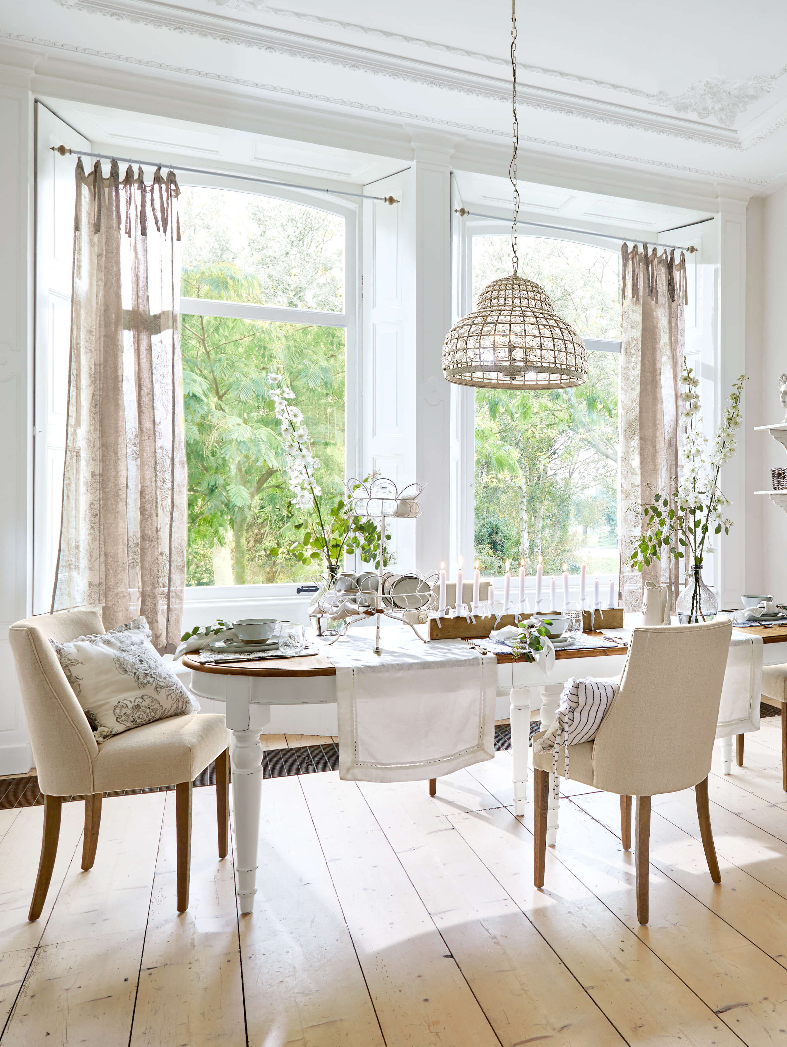 Esszimmer mit weißem Holztisch und beigen Stühlen, natürliches Licht und Dekorationen