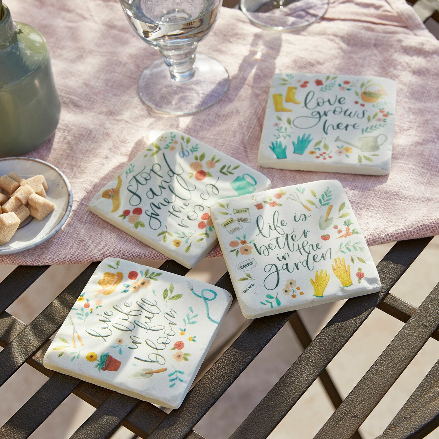 Untersetzer 4er Set Happy Set aus vier Keramikuntersetzern mit bunten Gartendesigns und Schriftzügen auf hellem Hintergrund