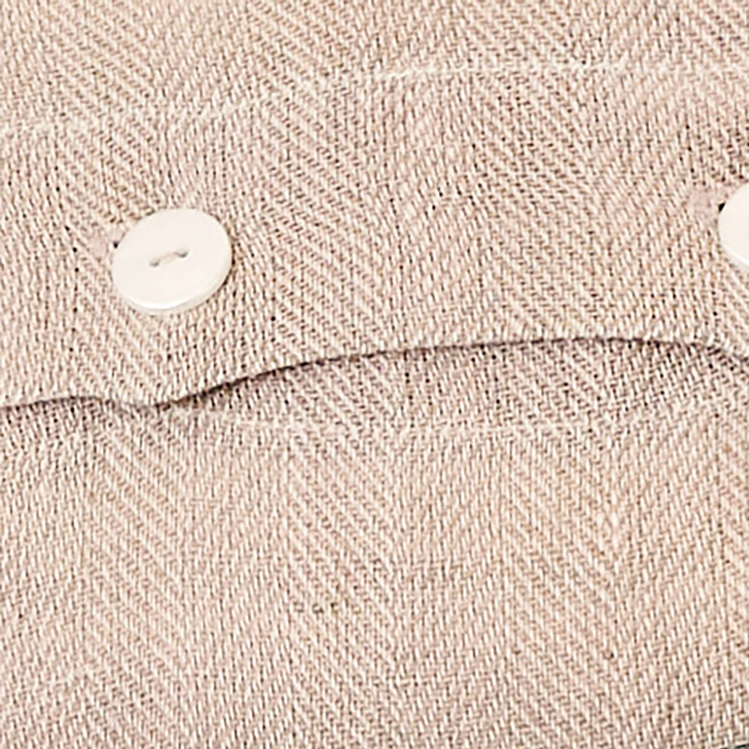Beiger Stoff mit Fischgrätmuster und weißem Knopf, detaillierte Textur des Materials