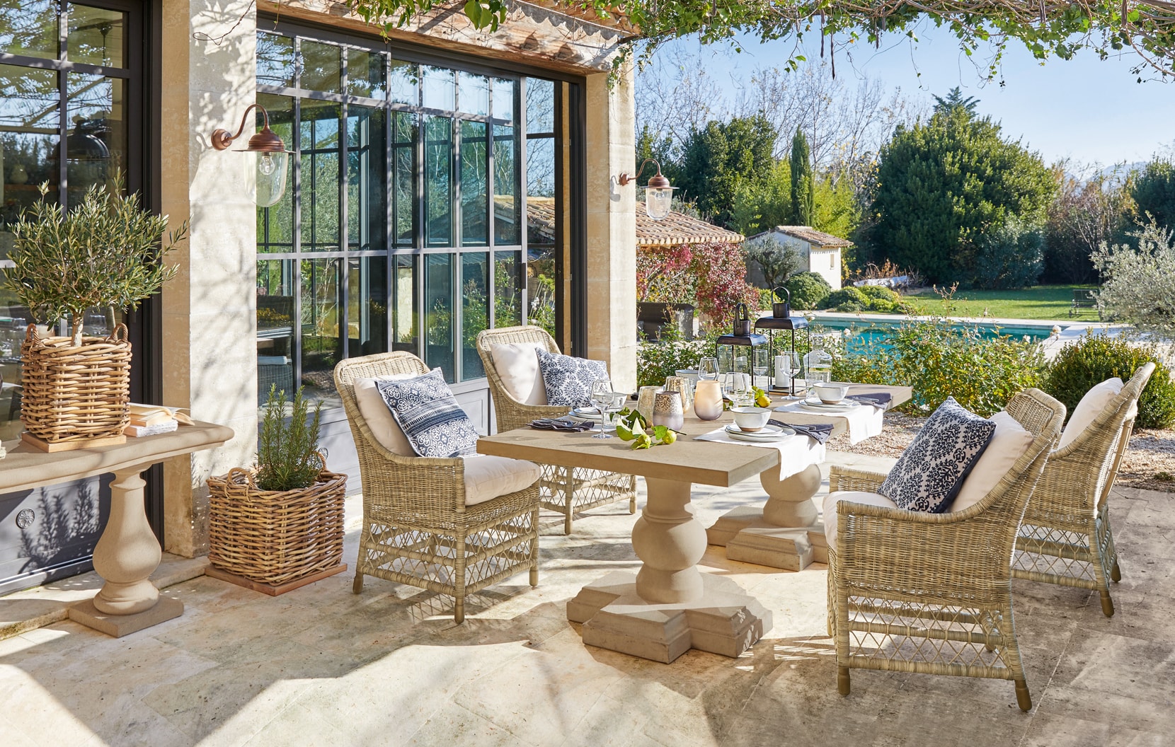 Gemütliche Terrasse mit Rattanmöbeln und Steintisch im mediterranen Stil mit Blick auf den Pool