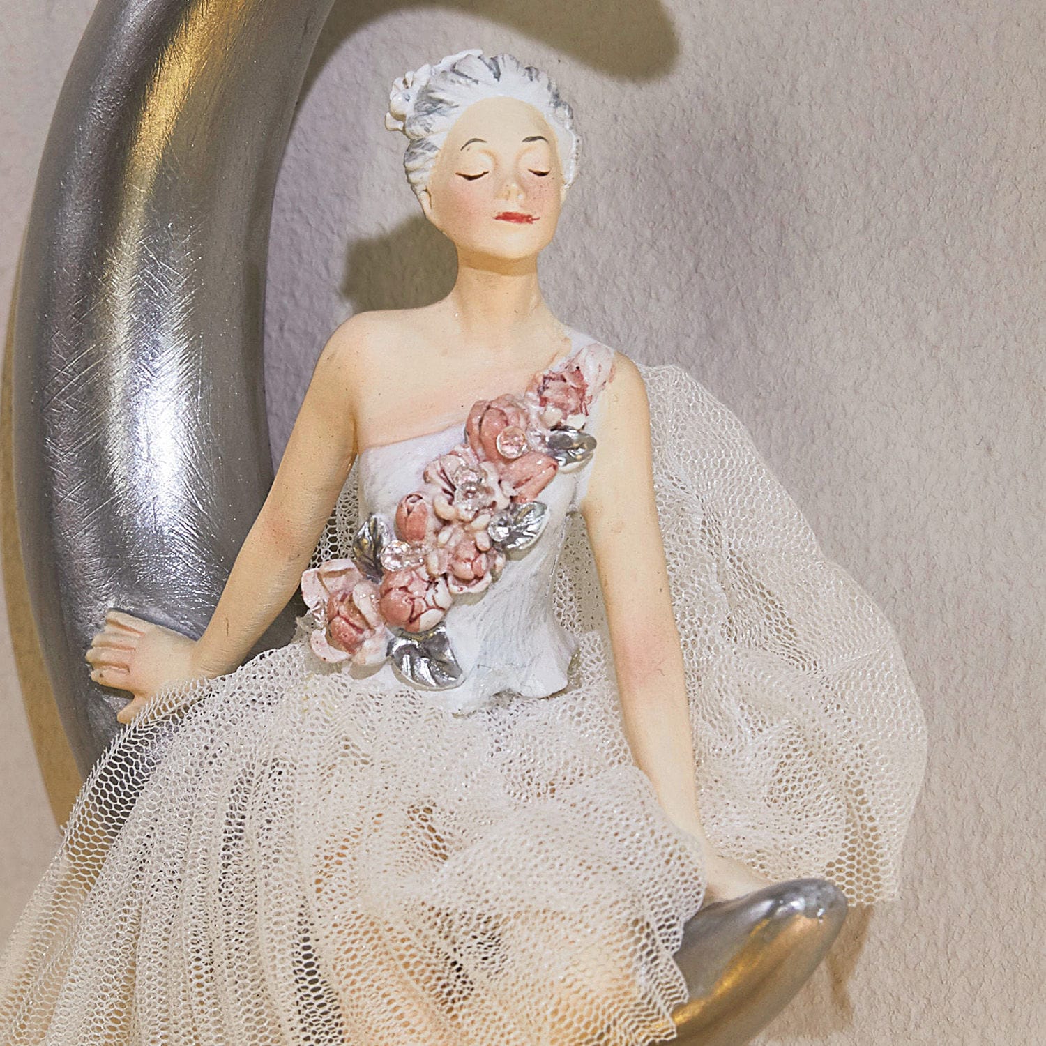 Figur einer Frau in weißem Tüllkleid mit rosa Blumen auf silbernem Halbmond als Wohnaccessoire
