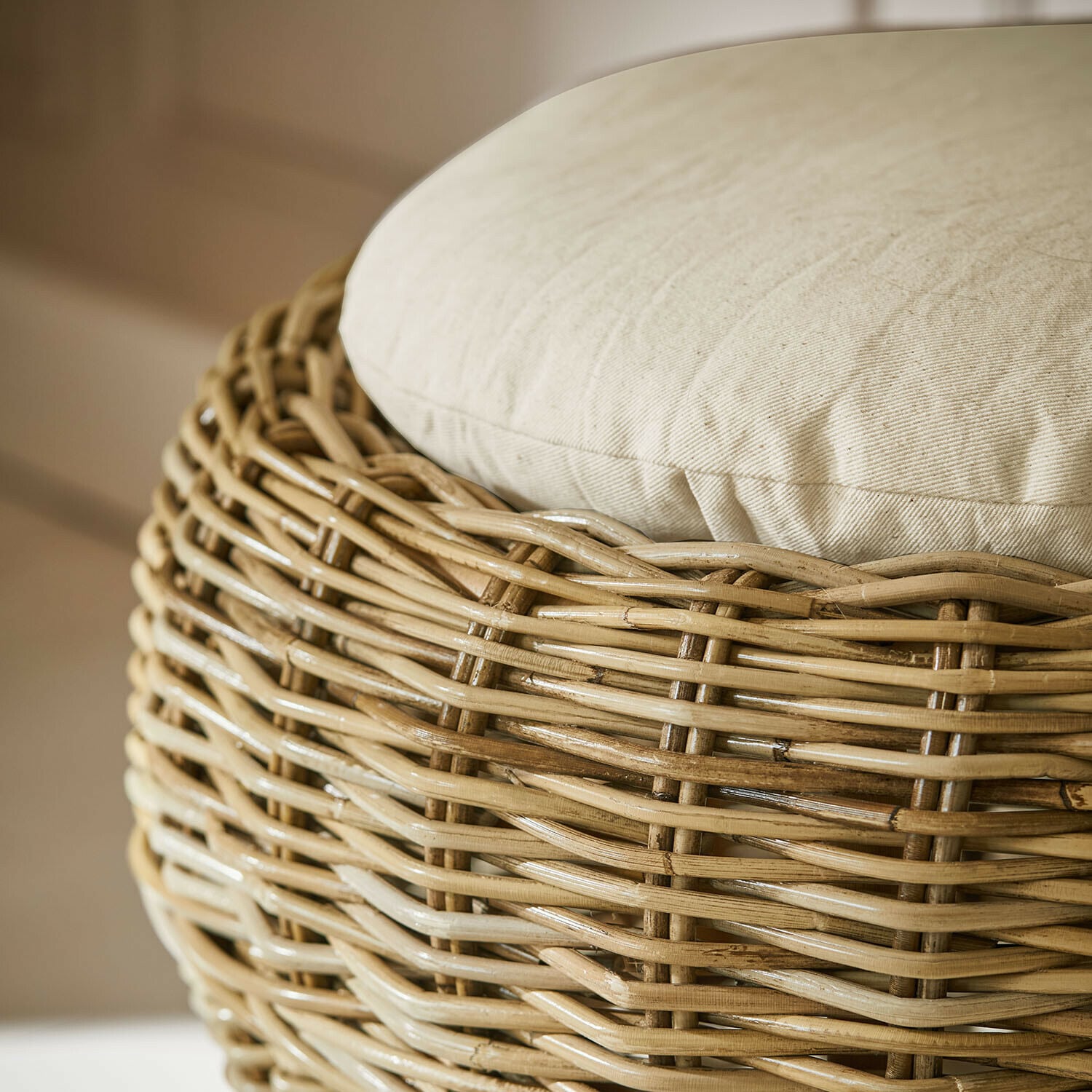 Beiger Rattan-Hocker mit cremefarbenem Kissen, gemütliches Wohnzimmermöbel