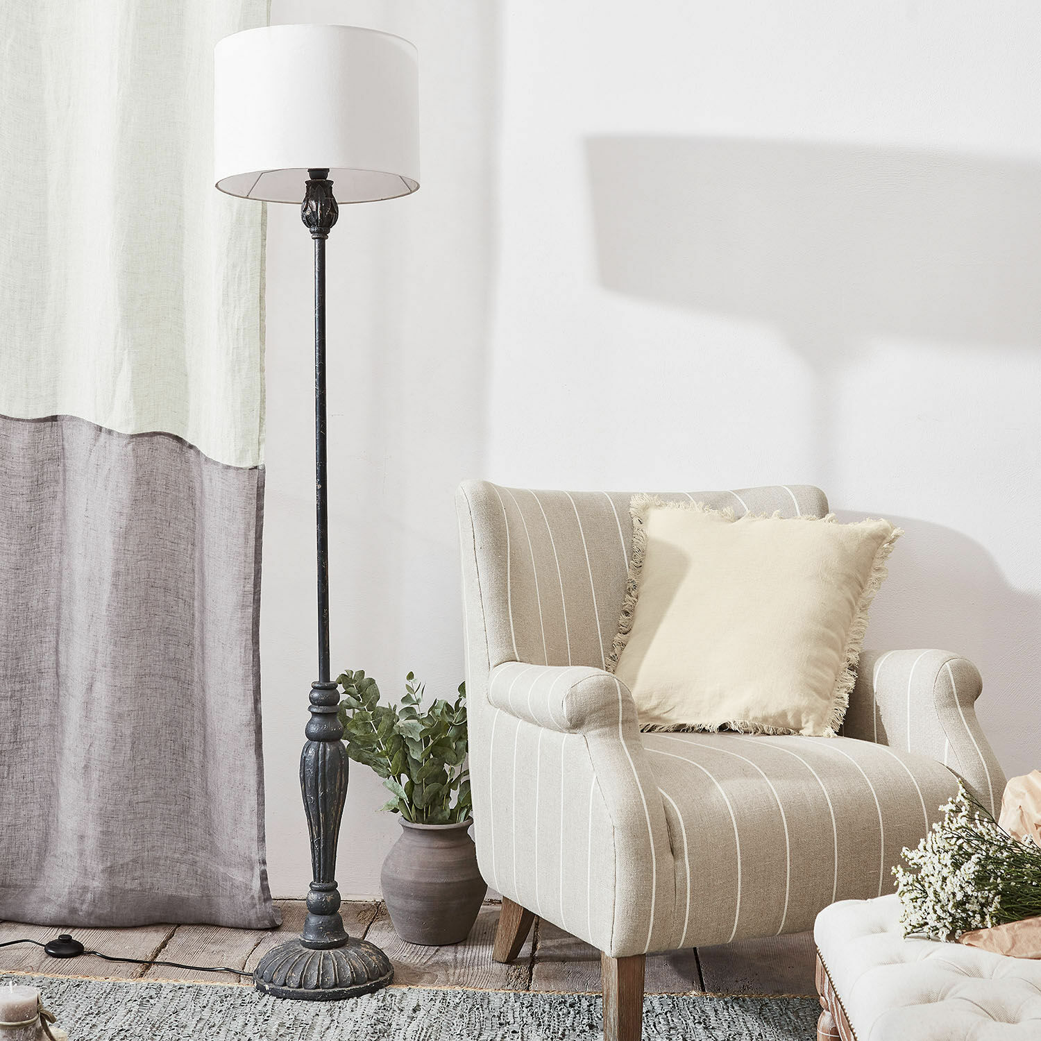 Beiger gestreifter Sessel mit cremefarbenem Kissen und schwarze Stehlampe aus Metall im Wohnzimmer