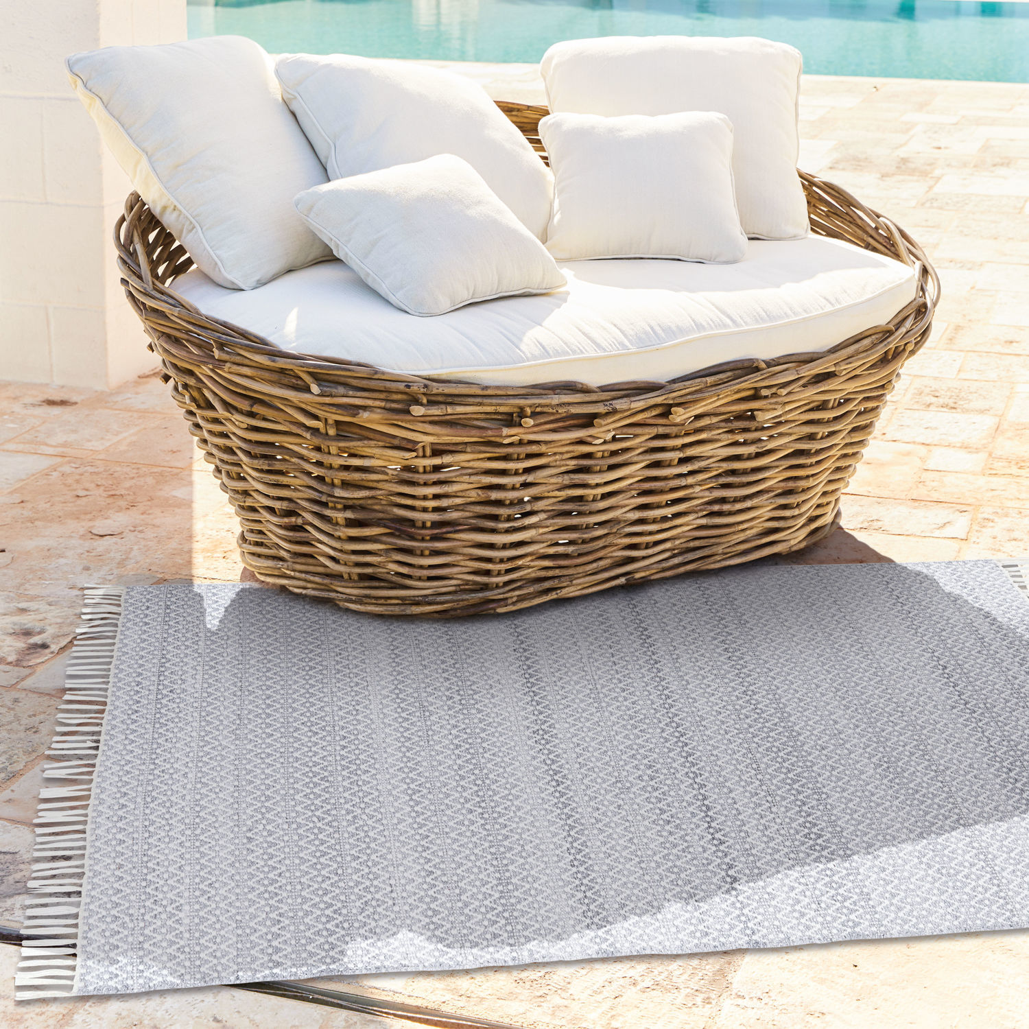 Ovale Rattan-Sofa mit cremefarbenen Kissen auf Terrasse am Pool, Gartenmöbel