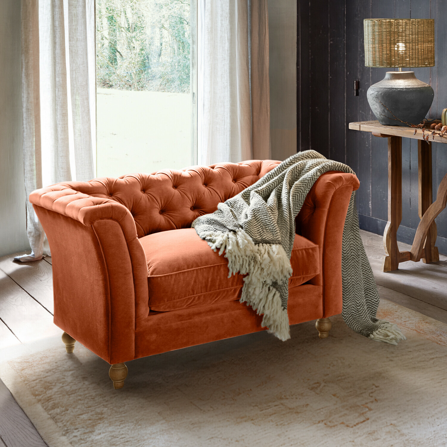 Sofa Clères Oranges Samt-Chesterfield-Sofa mit grauem Plaid in gemütlichem Wohnzimmer mit Lampe und Holztisch