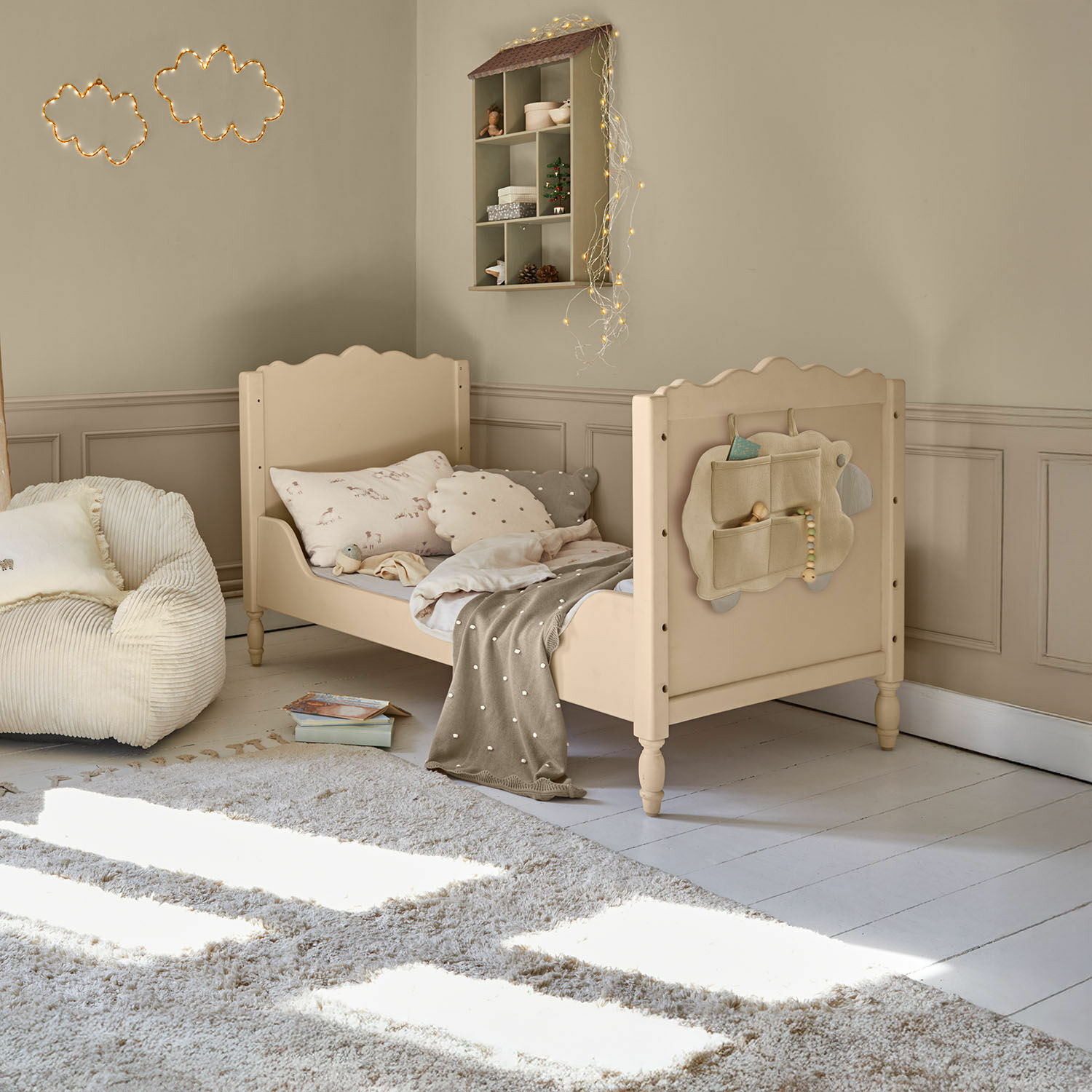 Beiges Kinderbett aus Holz mit weichen Kissen und Decke in gemütlichem Kinderzimmer