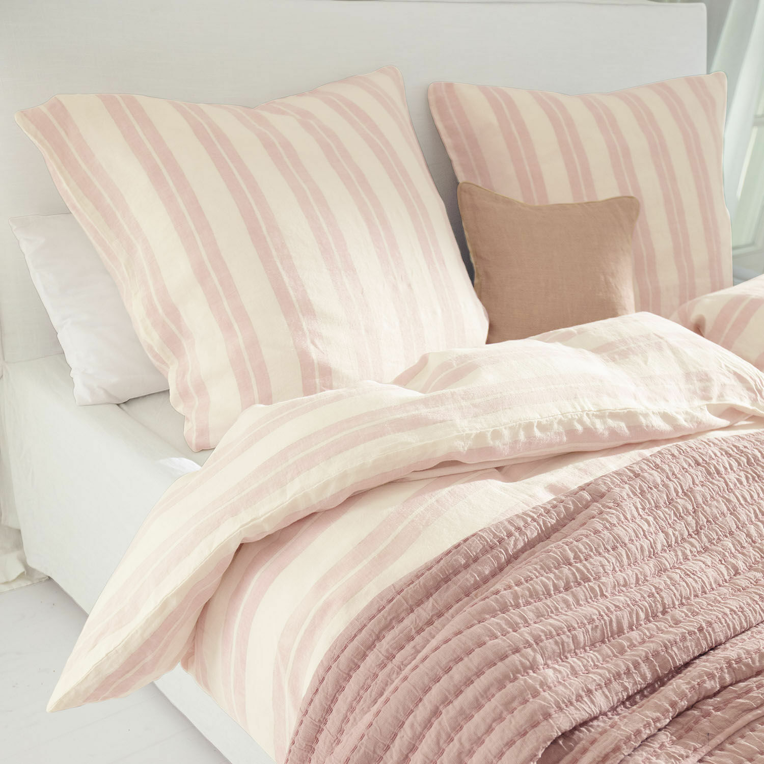 Bettwäsche Dordogne Bettwäsche aus Baumwolle in rosa-creme Streifen mit weicher rosa Decke auf hellem Bett