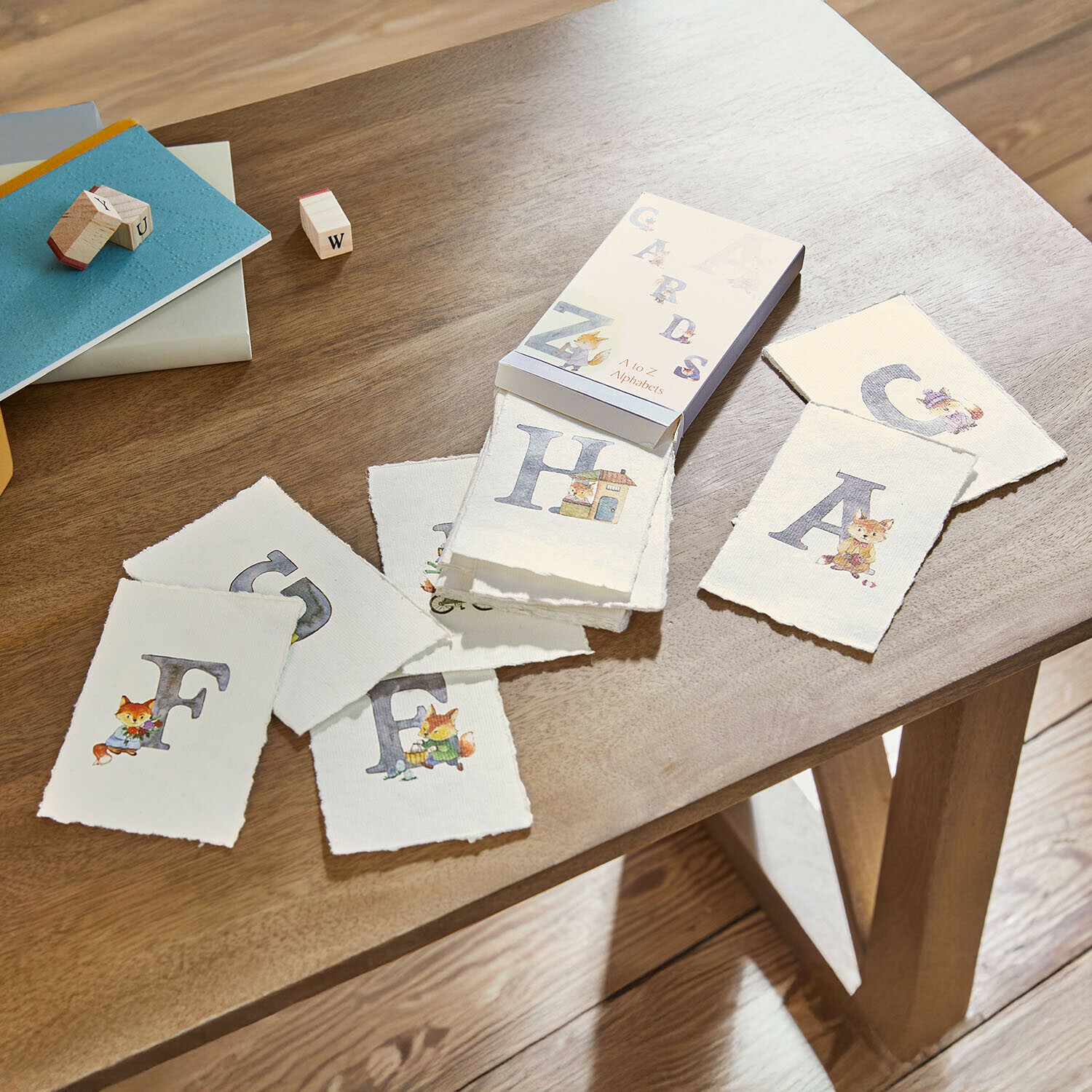 Set Lernkarten mit Alphabet und Tierillustrationen auf Holztisch zum Buchstabenerlernen