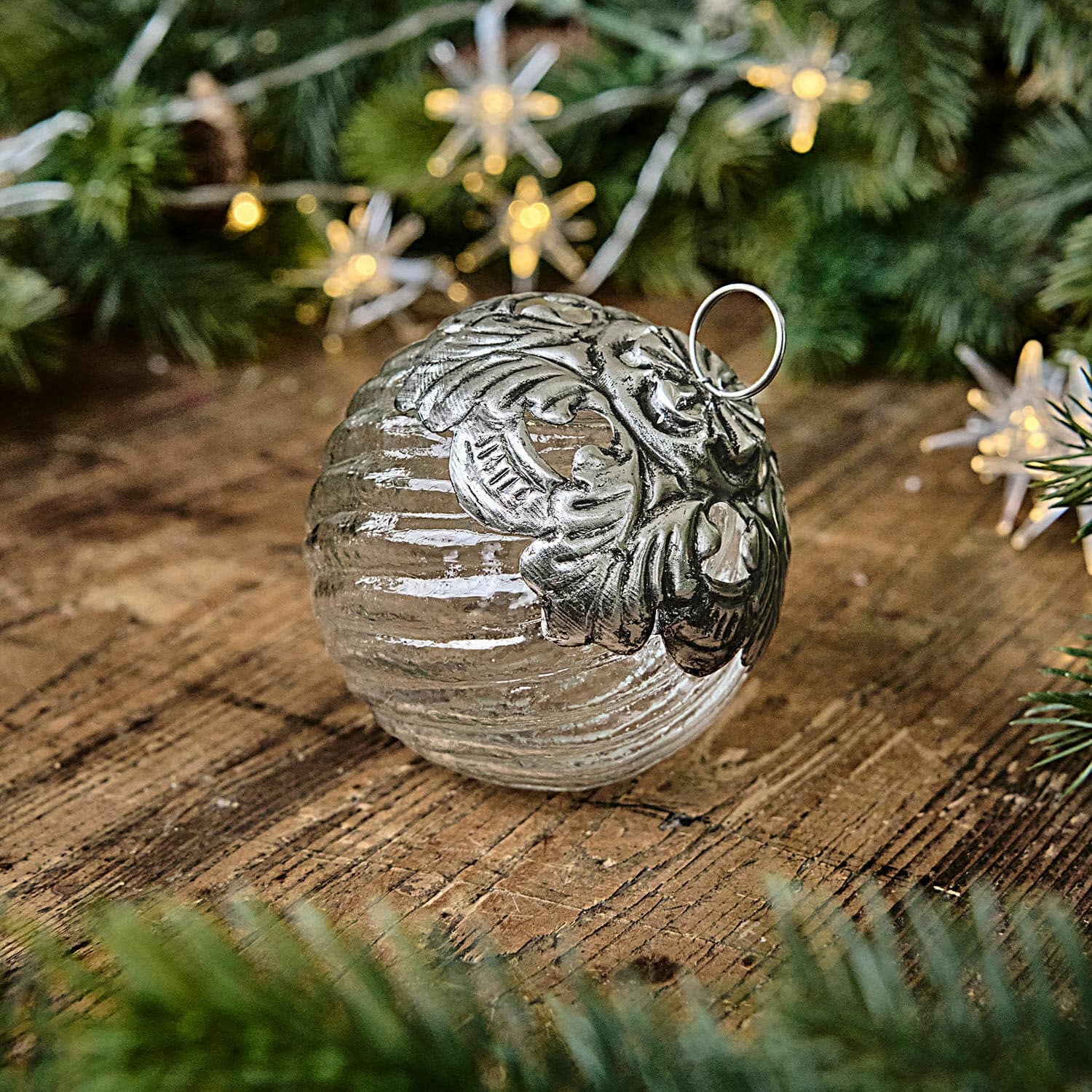 Weihnachtskugel Zoriline Glaskugel mit silberner Metallverzierung auf Holztisch mit grünen Tannenzweigen als Weihnachtsdeko