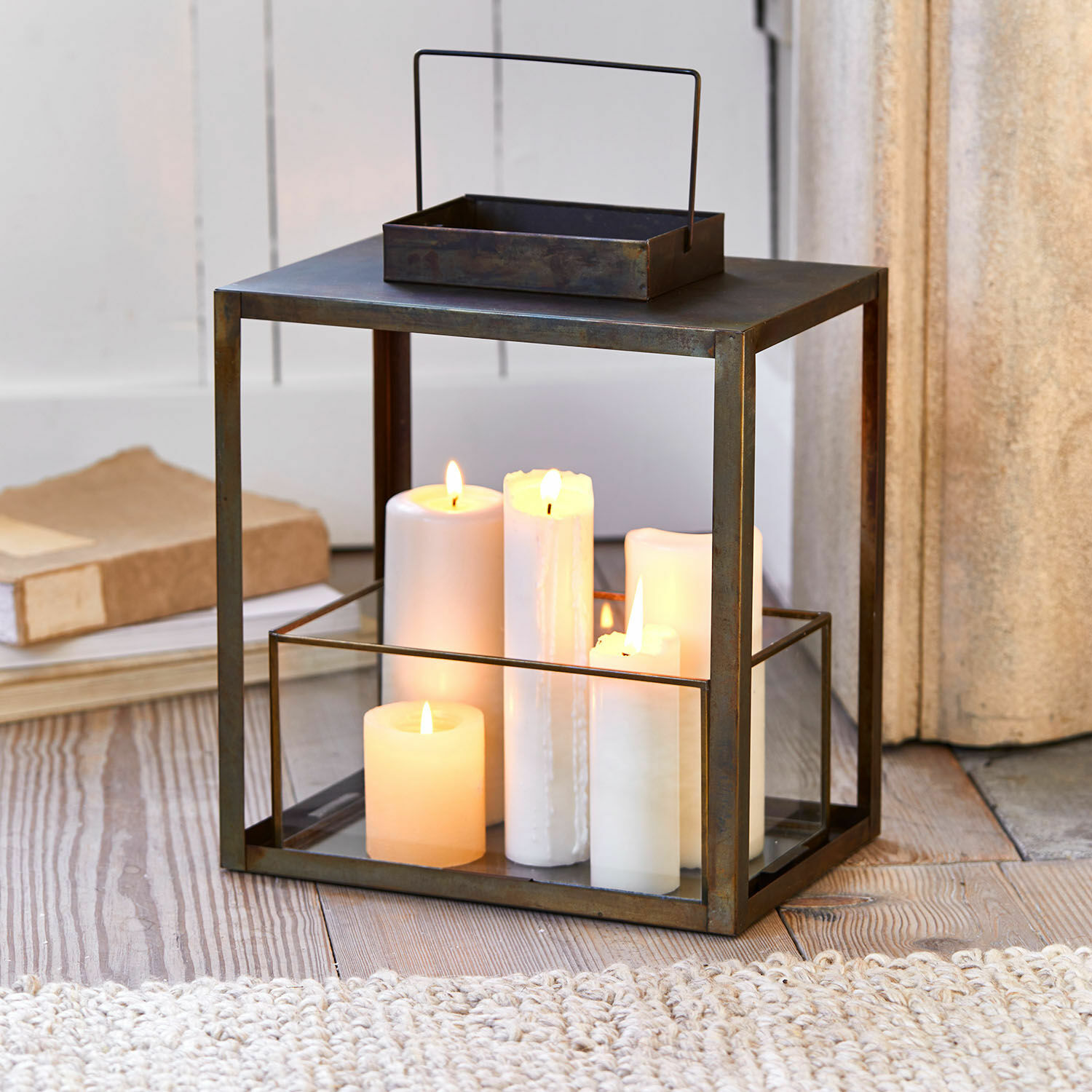 Laterne Abbracciante Metalllaterne mit klarem Glas und weißen brennenden Kerzen auf Holzboden, Wohnaccessoire