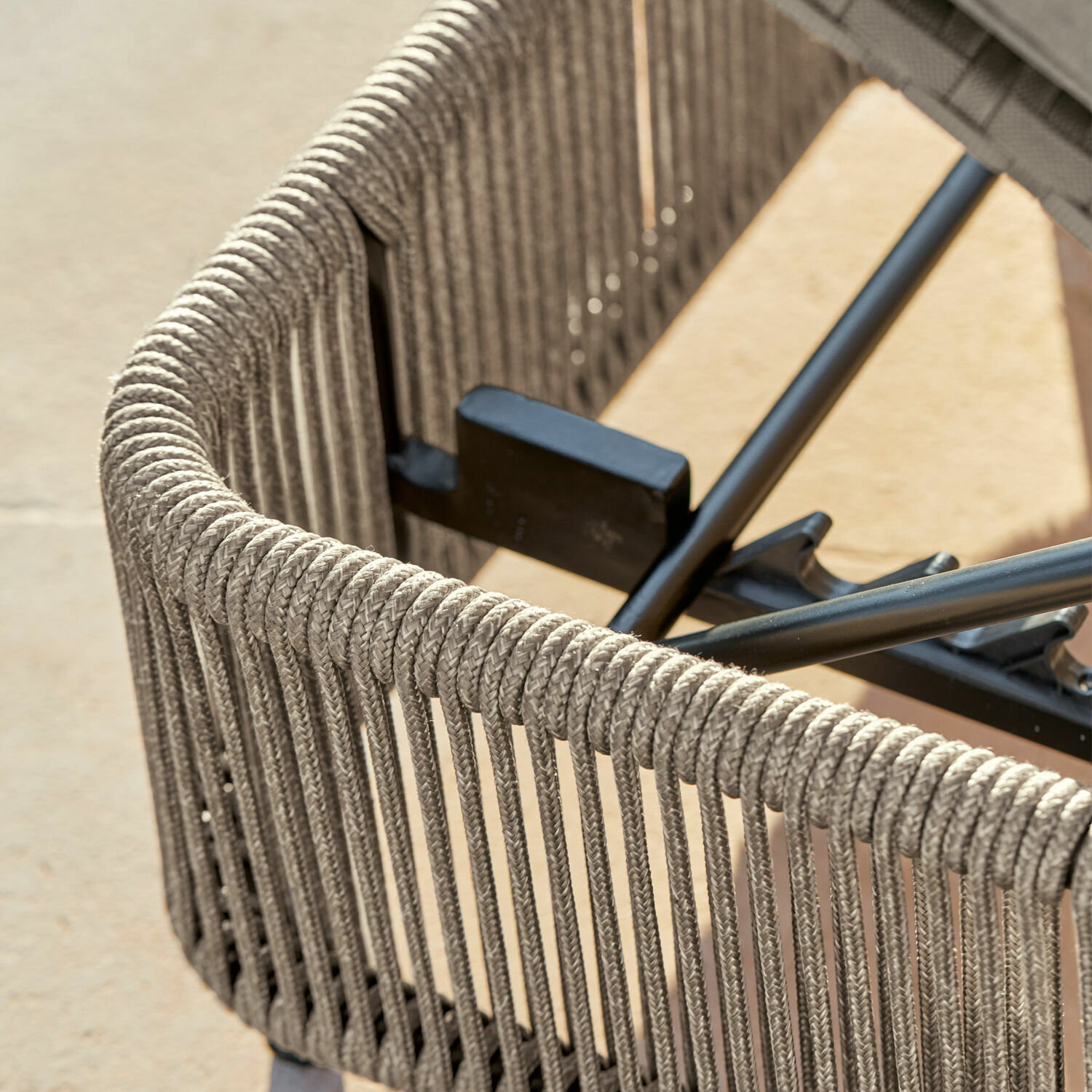 Detail eines grauen Gartenstuhls mit geflochtenem Seilrücken und Metallrahmen