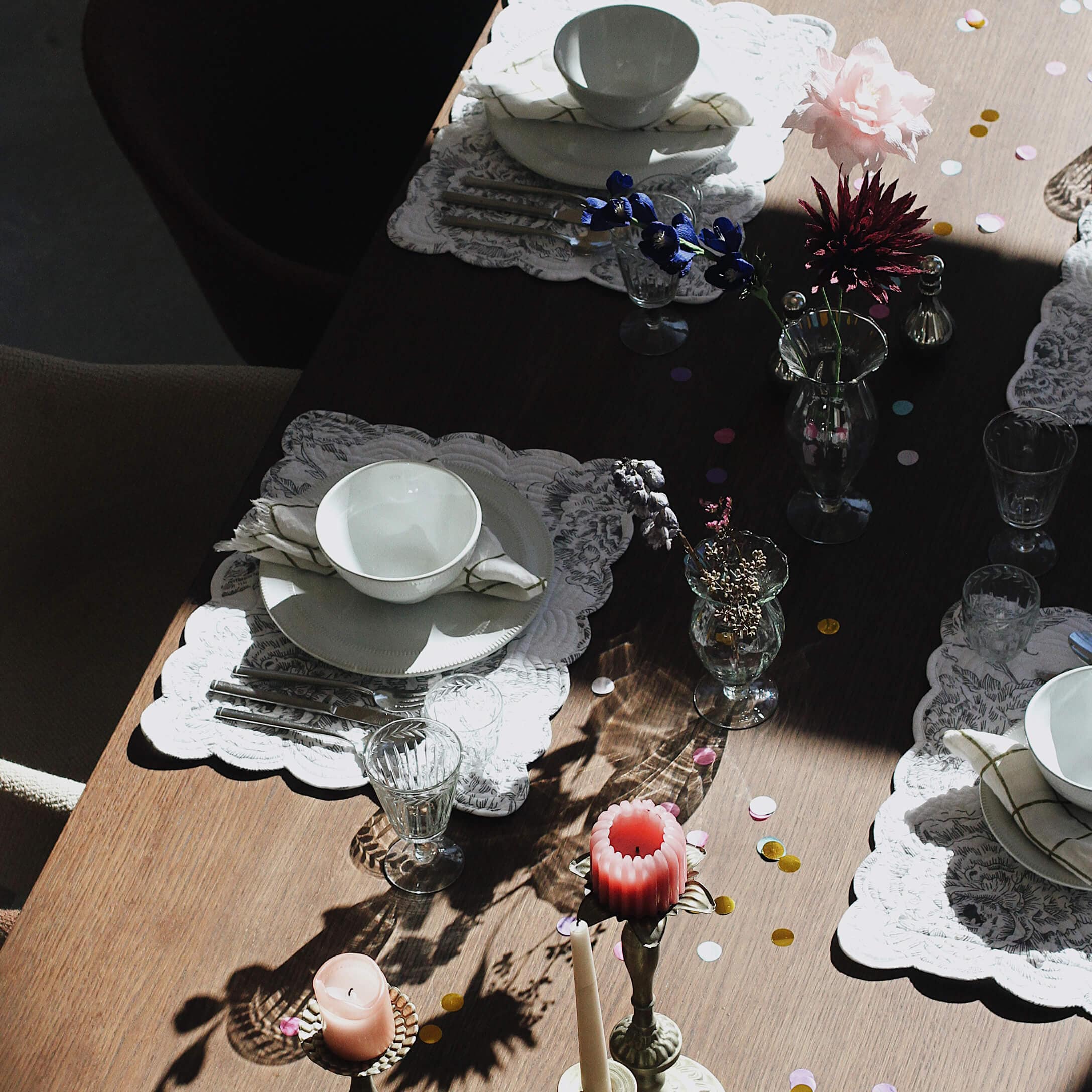 Eleganter gedeckter Tisch mit weißem Porzellan, Gläsern und Kerzen auf Holzplatte