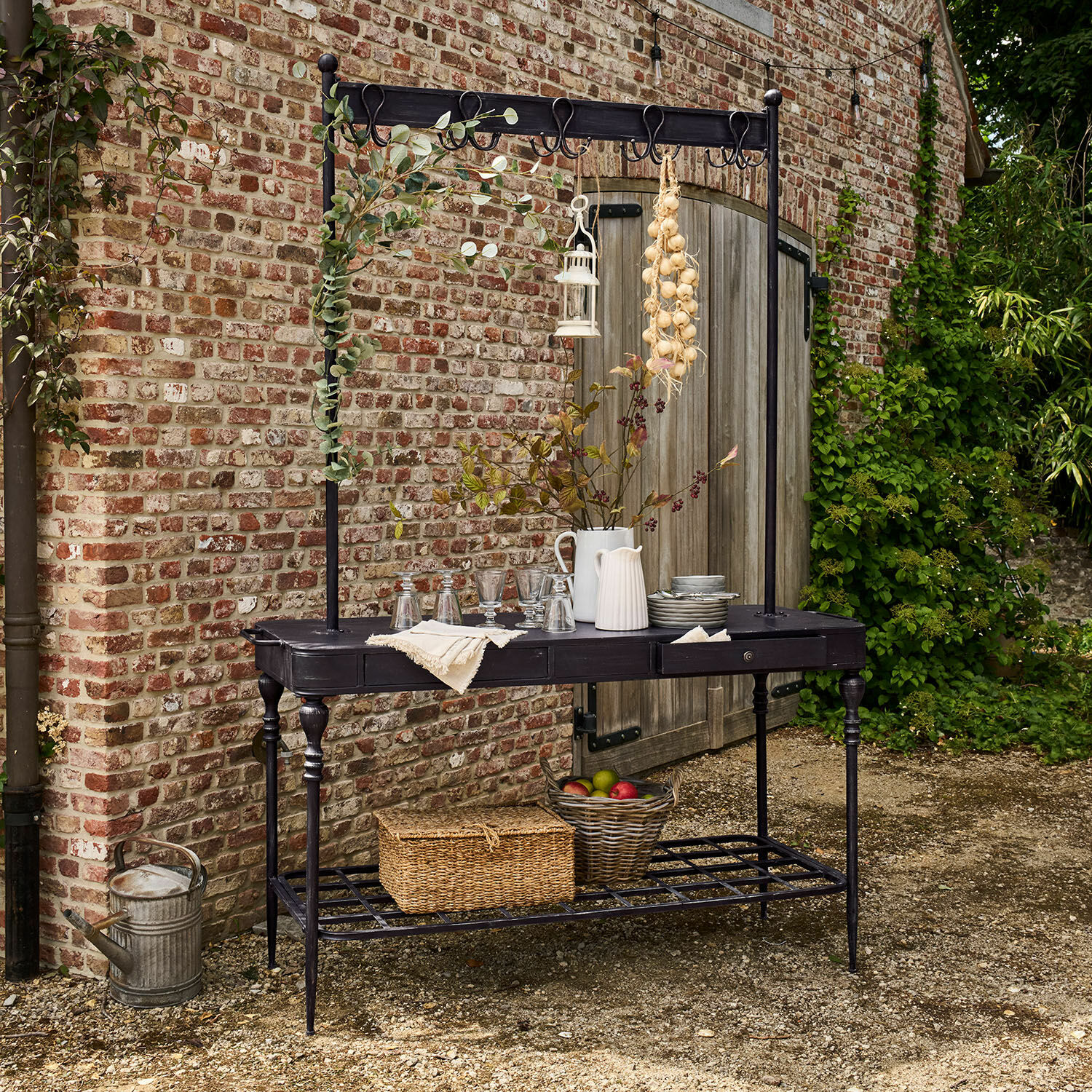 Regal Langmore Schwarzer Metall-Gartentisch mit Haken und Ablage, dekoriert mit Krügen und Obstkorb
