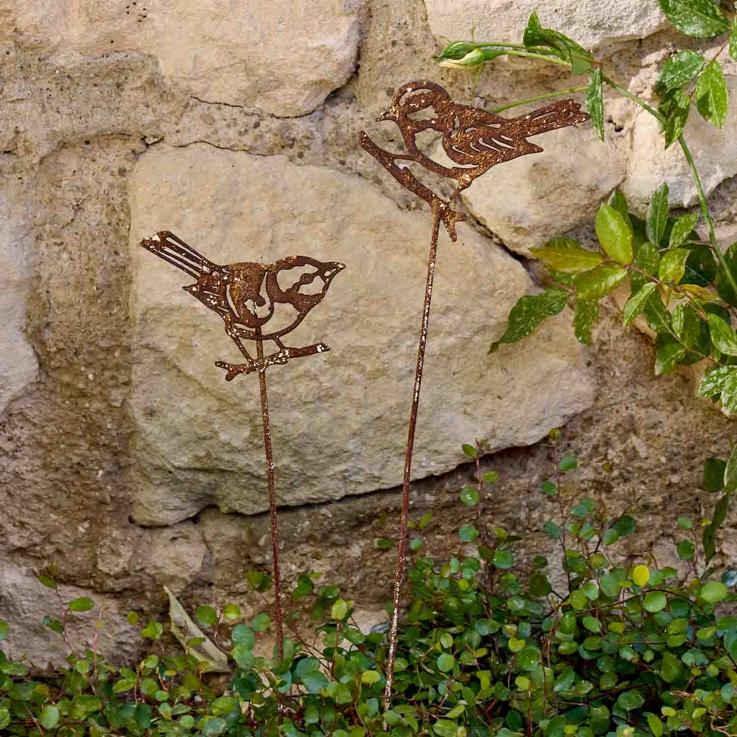 Dekorative rostige Metallvögel auf Stäben als Gartendeko für Pflanzen und Beete
