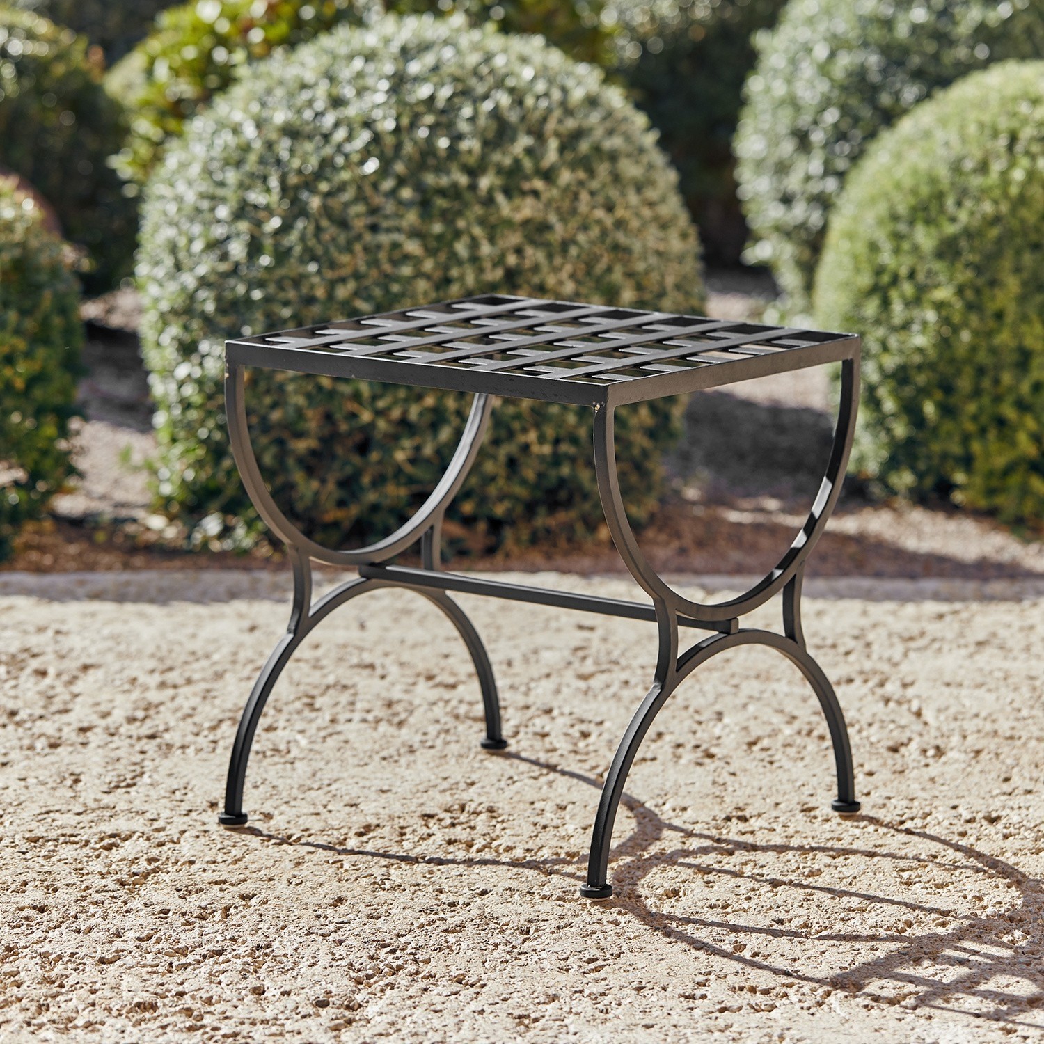 Schwarzer Metall-Gartentisch mit Gitterplatte und dekorativen Beinen auf Terrasse