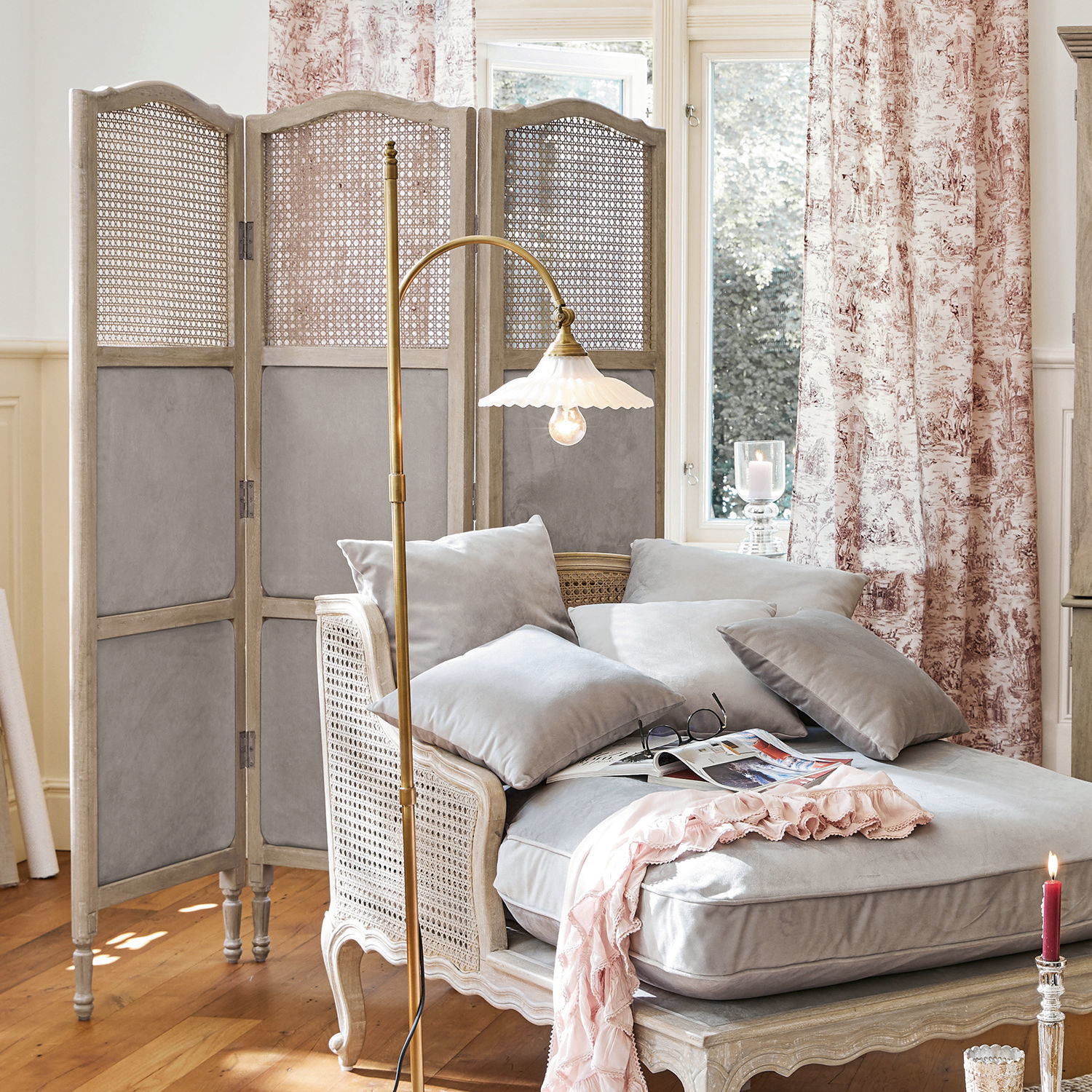 Graue Samt-Chaiselongue mit Kissen und hellem Holzrahmen im Wohnzimmer mit Paravent und Stehlampe
