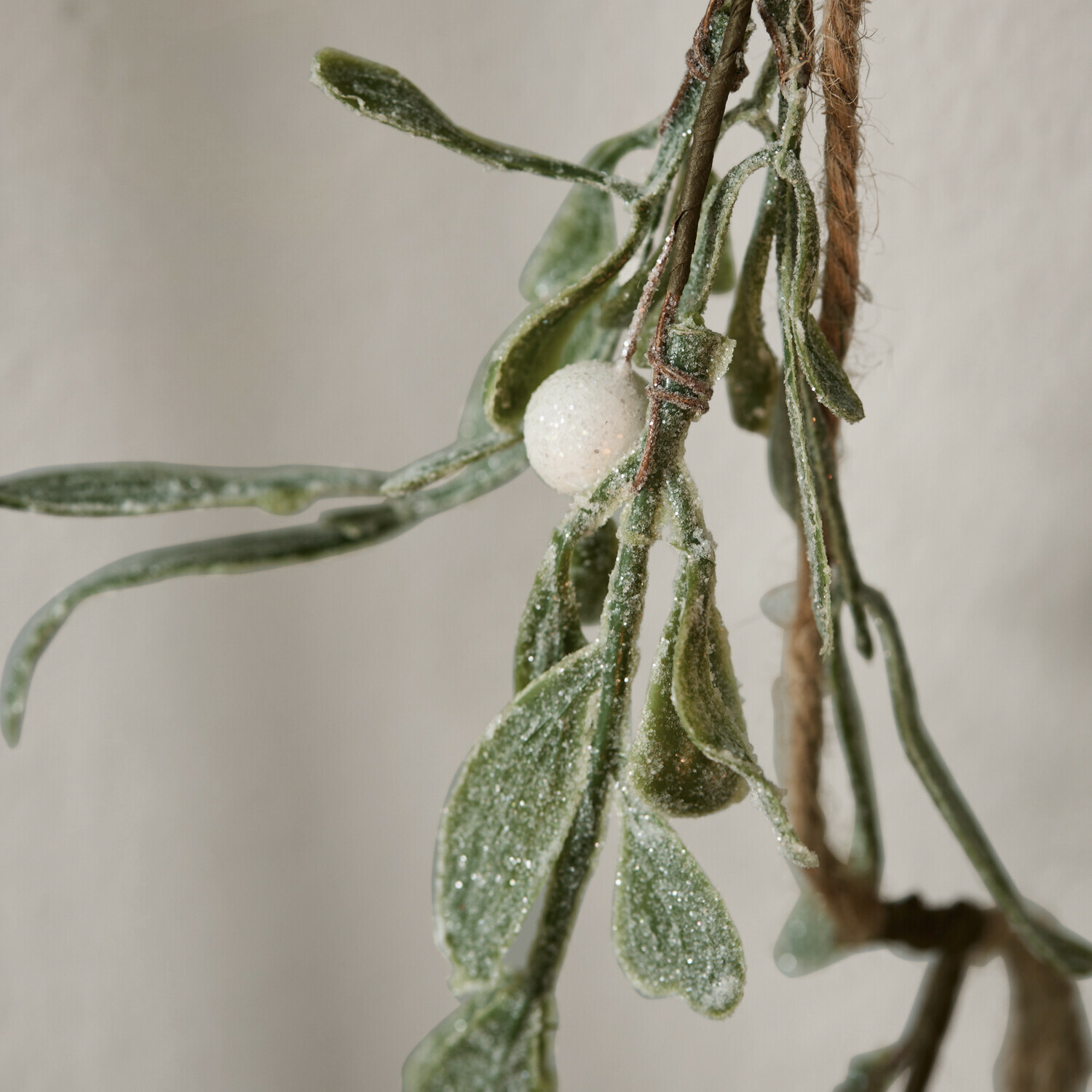 Zweig mit grünen Mistelblättern und weißer Kugel, frostige Weihnachtsdekoration
