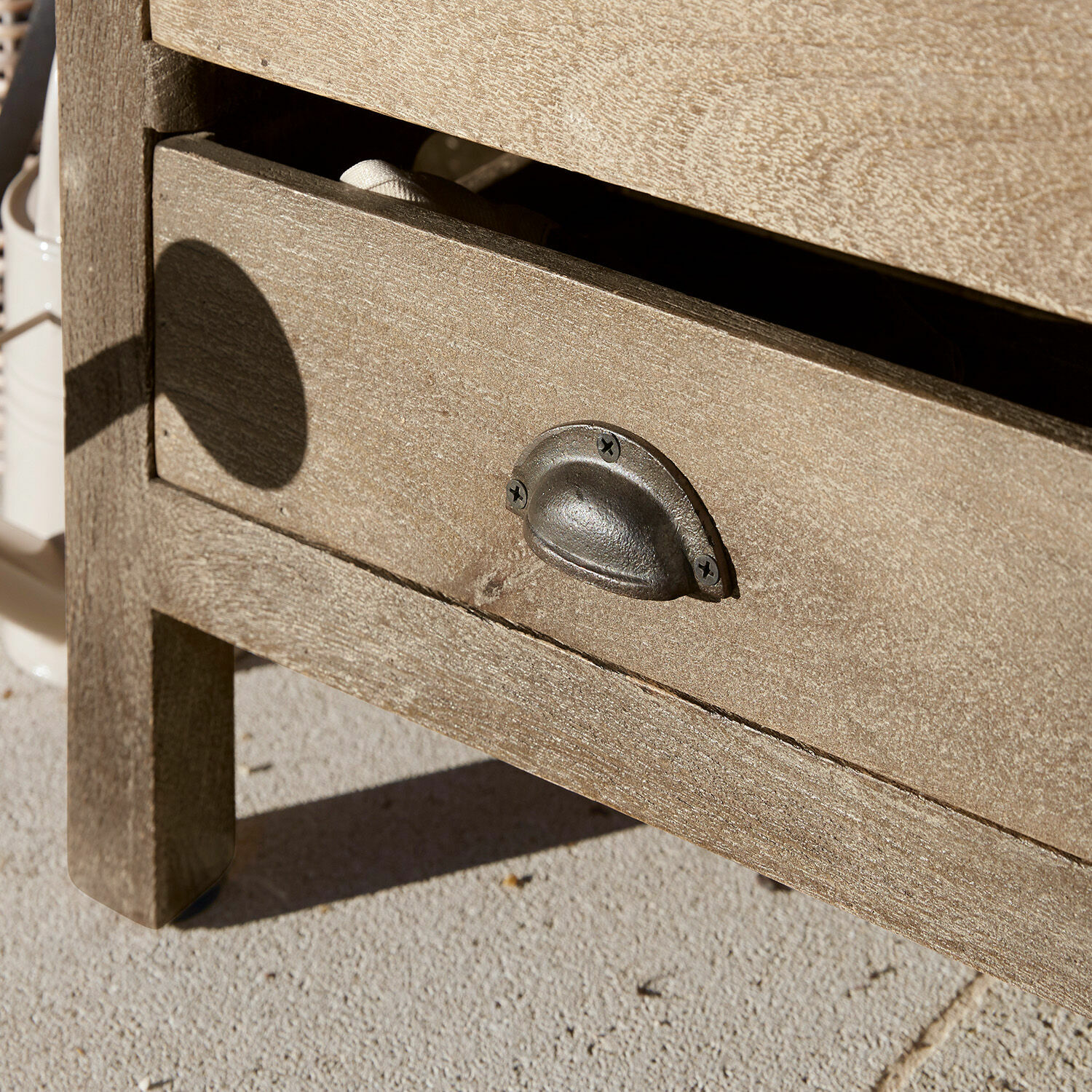 Schublade aus hellem Holz mit vintage Metallgriff auf hellem Steinboden