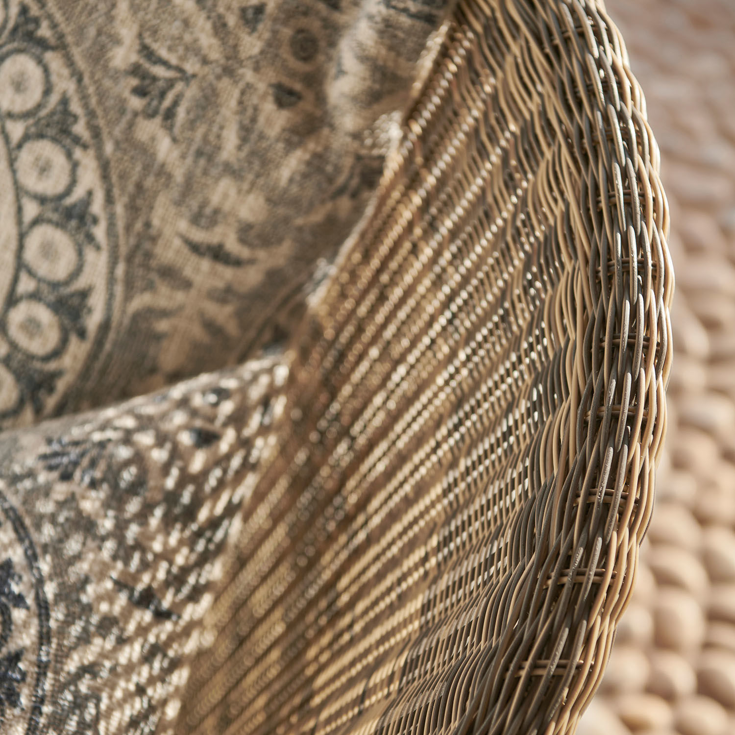 Natürlicher Korbsessel aus Rattan mit gemustertem Kissen in Beige- und Brauntönen für Wohnzimmer