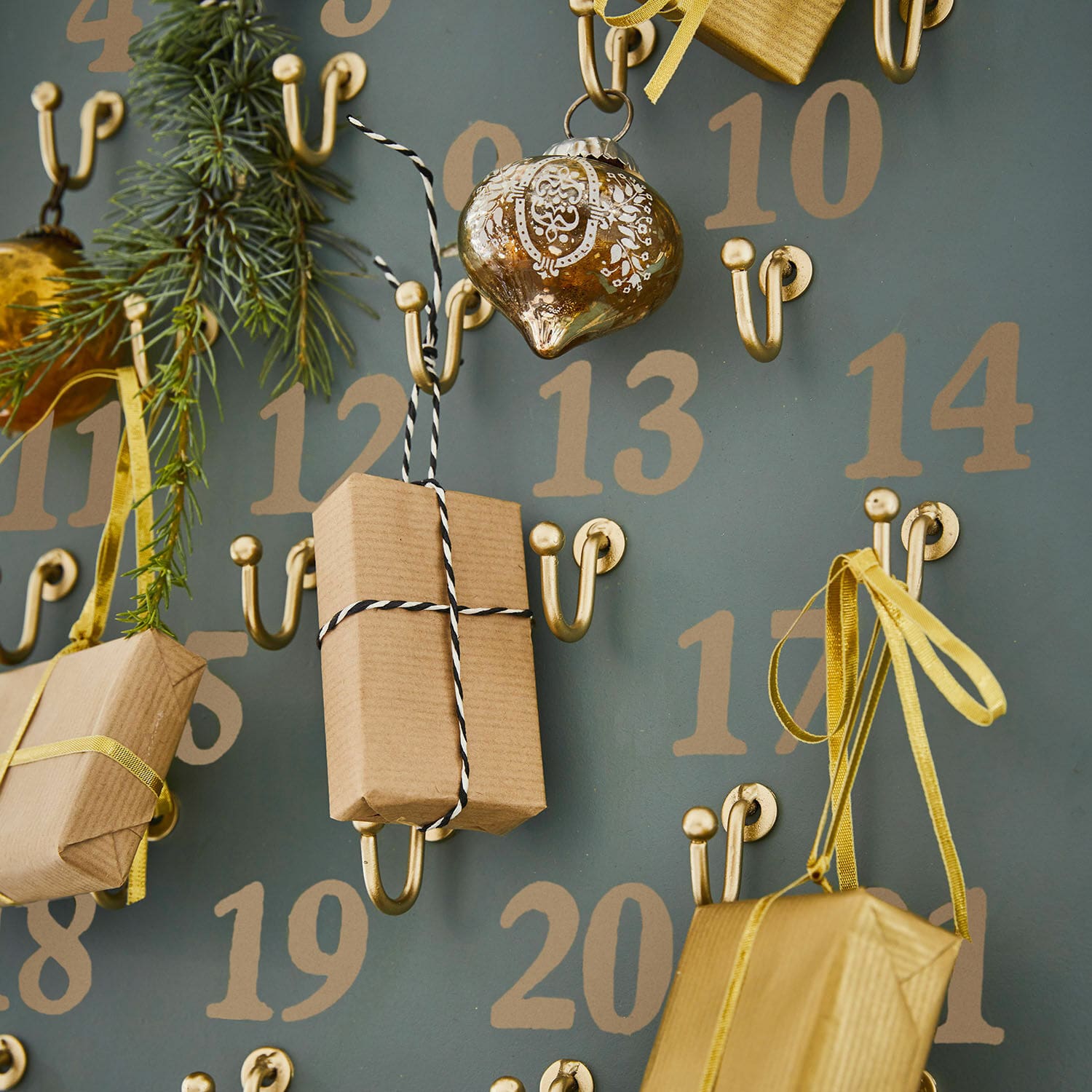 Adventskalender mit goldfarbenen Metallhaken und Geschenken in braunem Packpapier