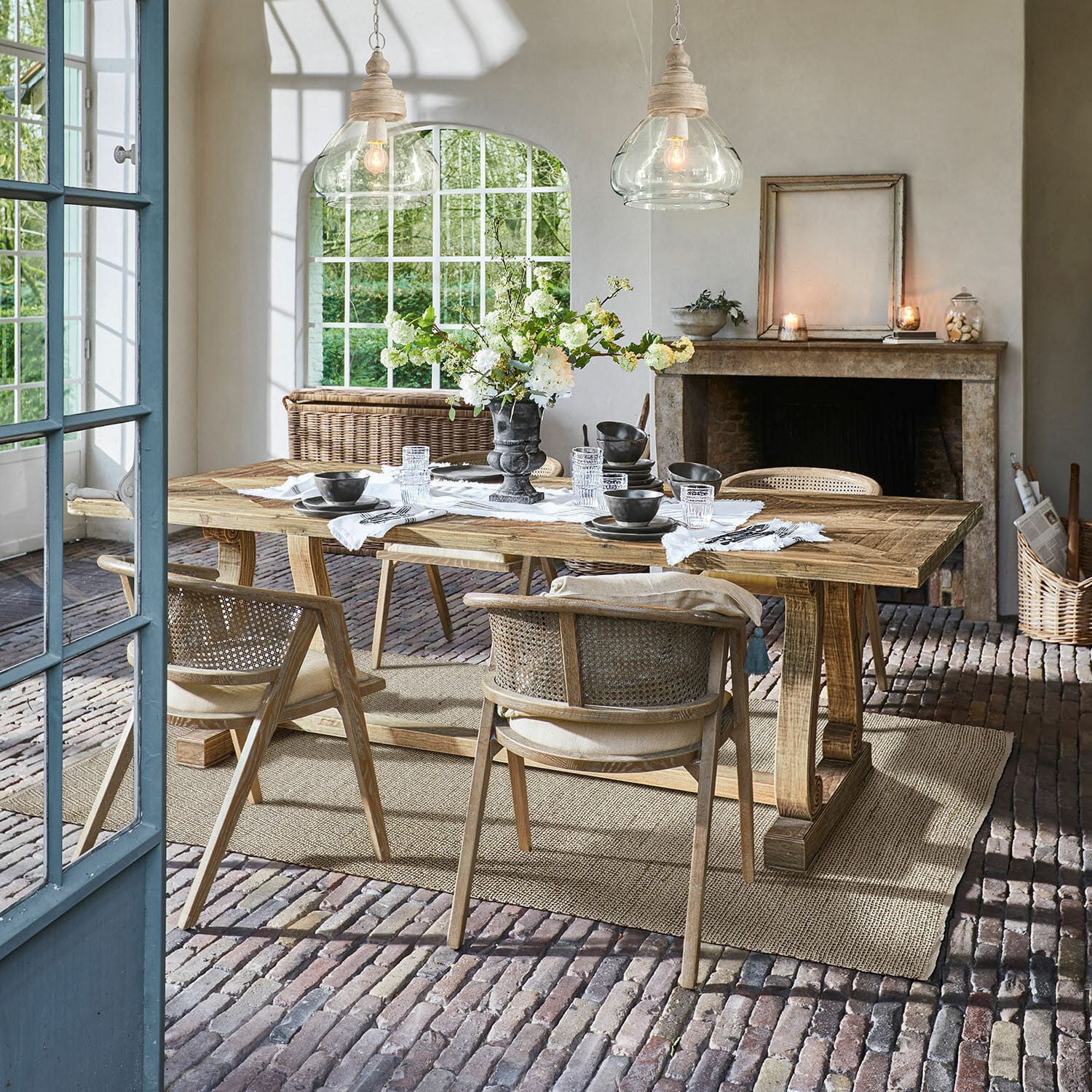 Tisch Campbelltown Esszimmer mit Holztisch und Korbstühlen auf Ziegelboden mit Blumendekoration
