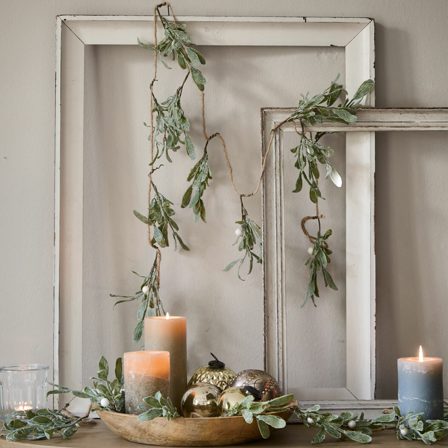 Girlande Mistletoe Dekorative Girlande mit grünen Blättern und weißen Beeren vor weißen Holzrahmen, Kerzen und Deko