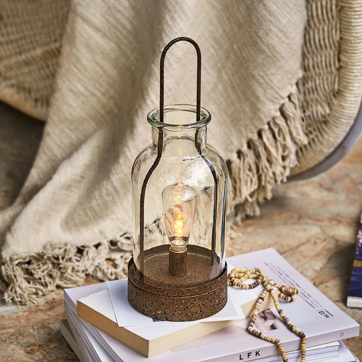 Glaslaterne mit rostfarbener Metallbasis, dekorative Tischlampe auf Büchern