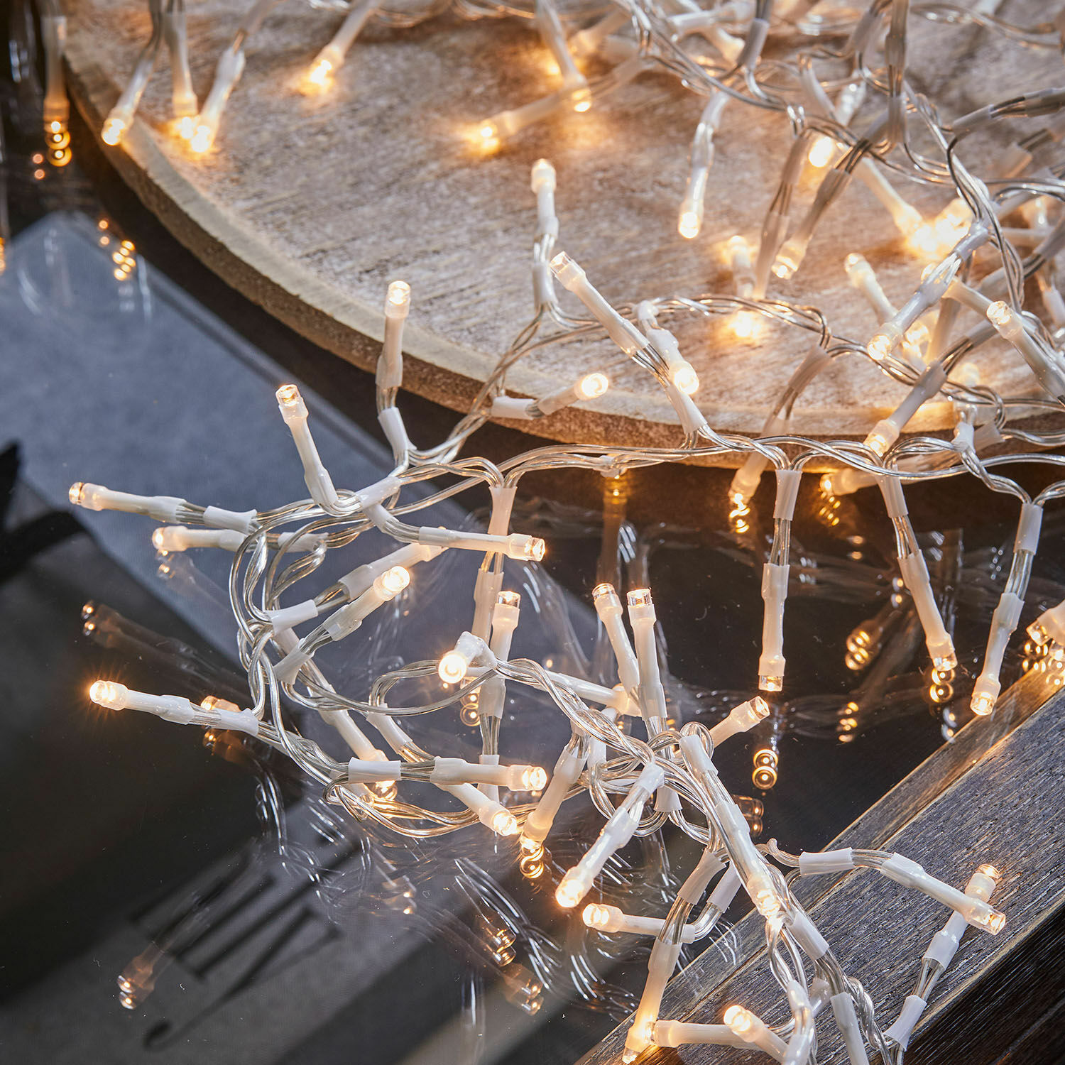 LED-Lichterkette mit weißem Kabel auf Glas- und Holztisch, festliche Weihnachtsdekoration