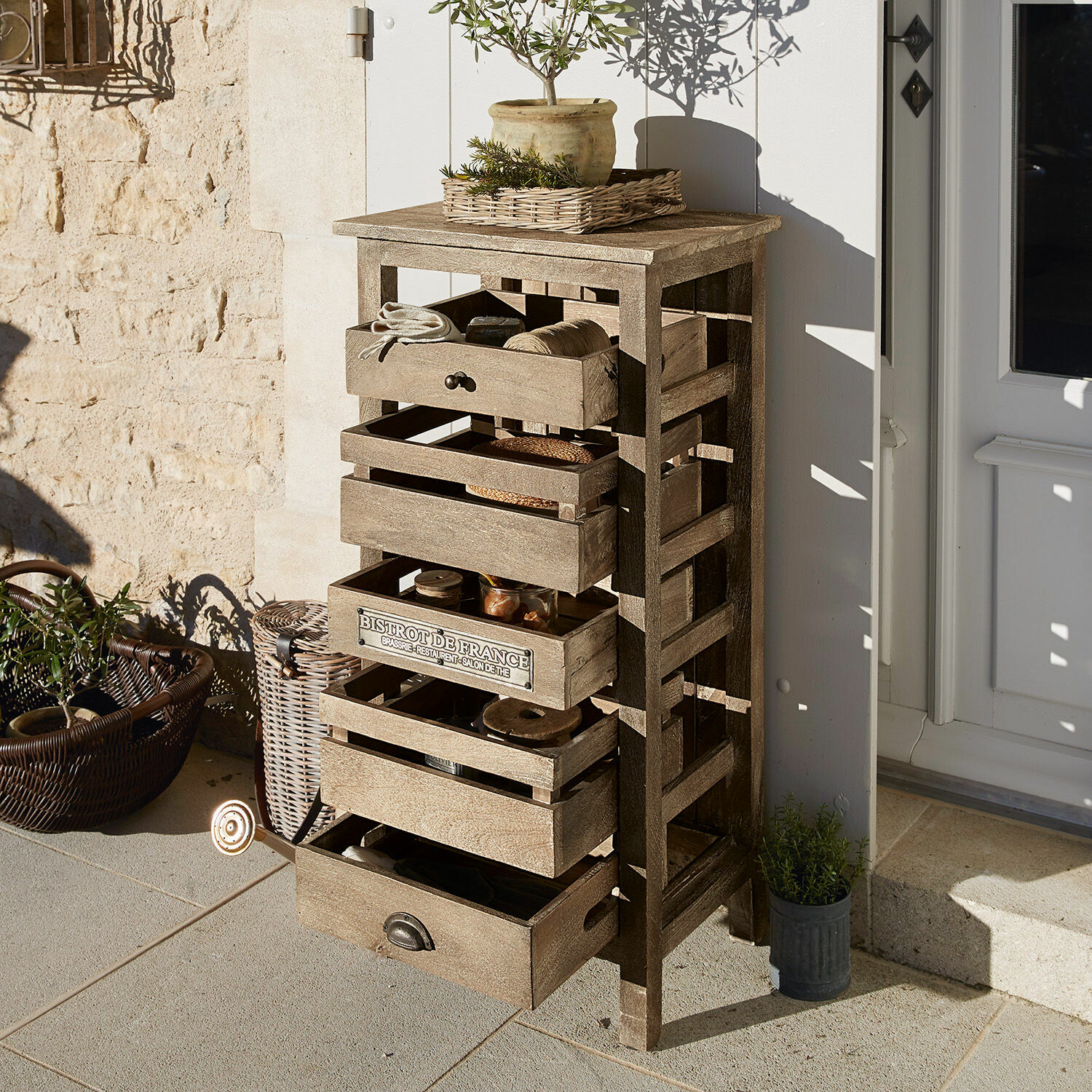 Holzkommode in Naturfarbe mit Schubladen auf Terrasse, dekoriert mit Pflanzen und Accessoires
