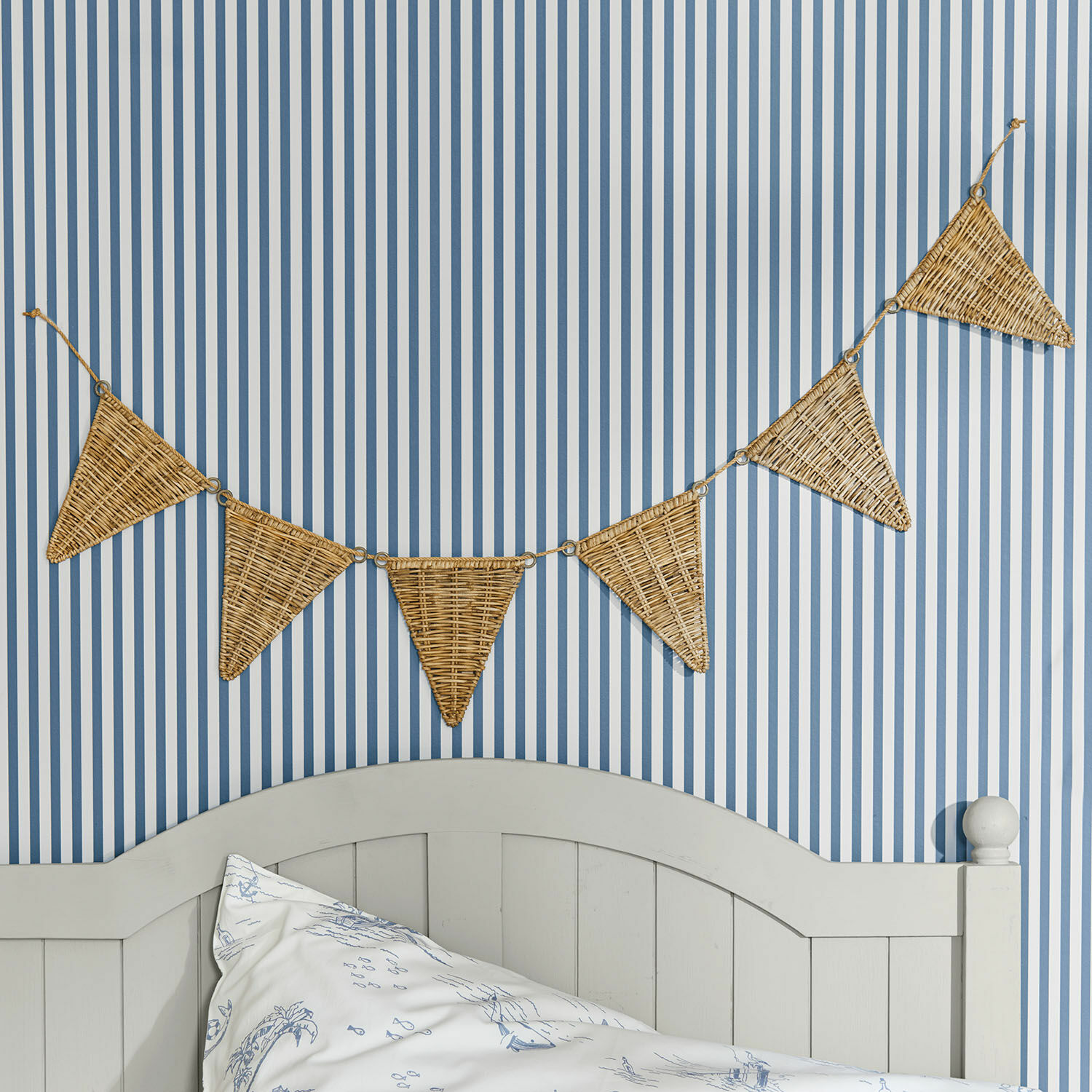 Wimpelgirlande Anglemont Dekorative Wimpelkette aus geflochtenem Rattan an blau-weiß gestreifter Wand im Schlafzimmer