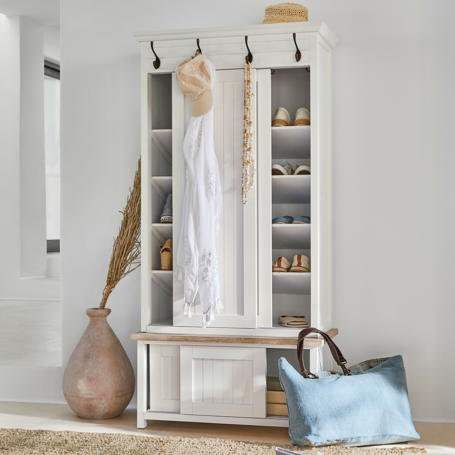 Garderobe Remerton Weisse Holzschuhschrank mit Haken und Regalen, blaue Tasche und Strohhut als Dekoration