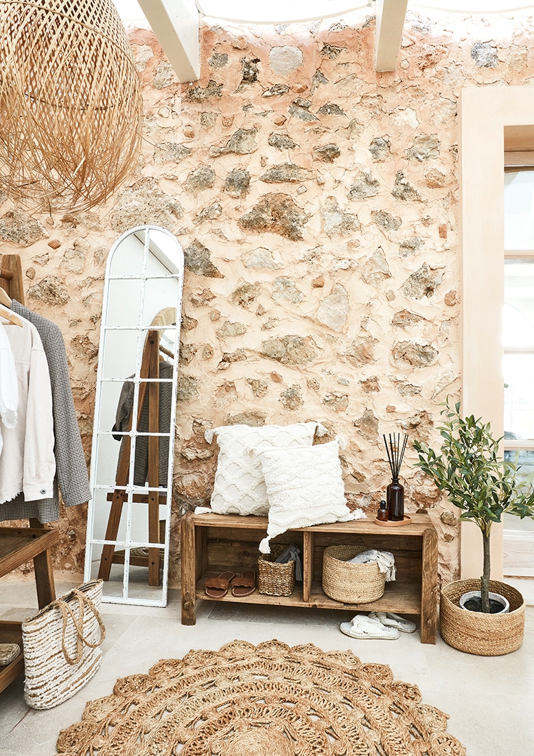 Gemütliche Ecke mit Holzbank, weißen Kissen und natürlichem Jute-Teppich im Boho-Stil