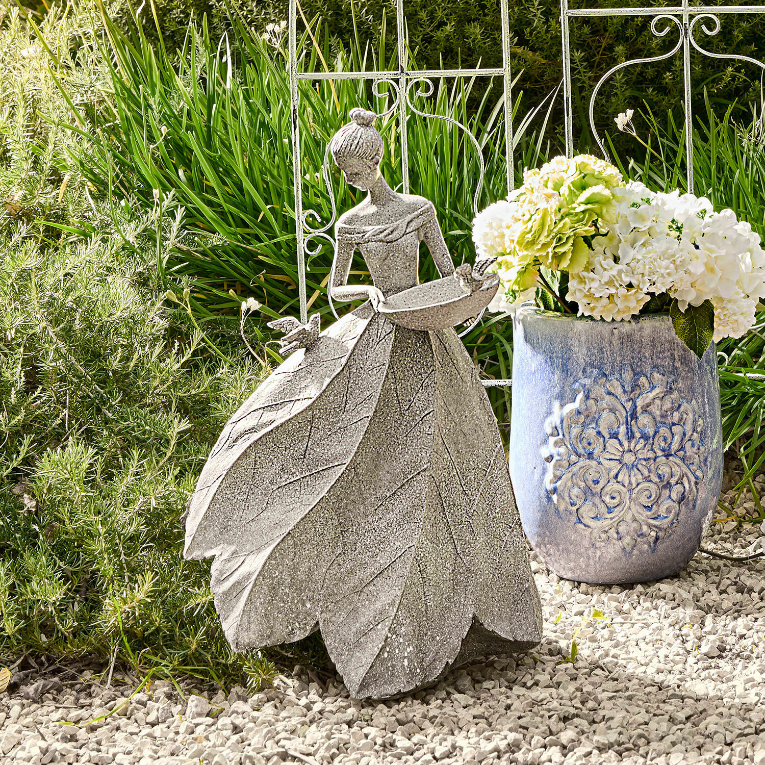 Skulptur Sullon Gartendekoration aus grauem Stein mit Frauenfigur und Blätterkleid auf Kiesboden