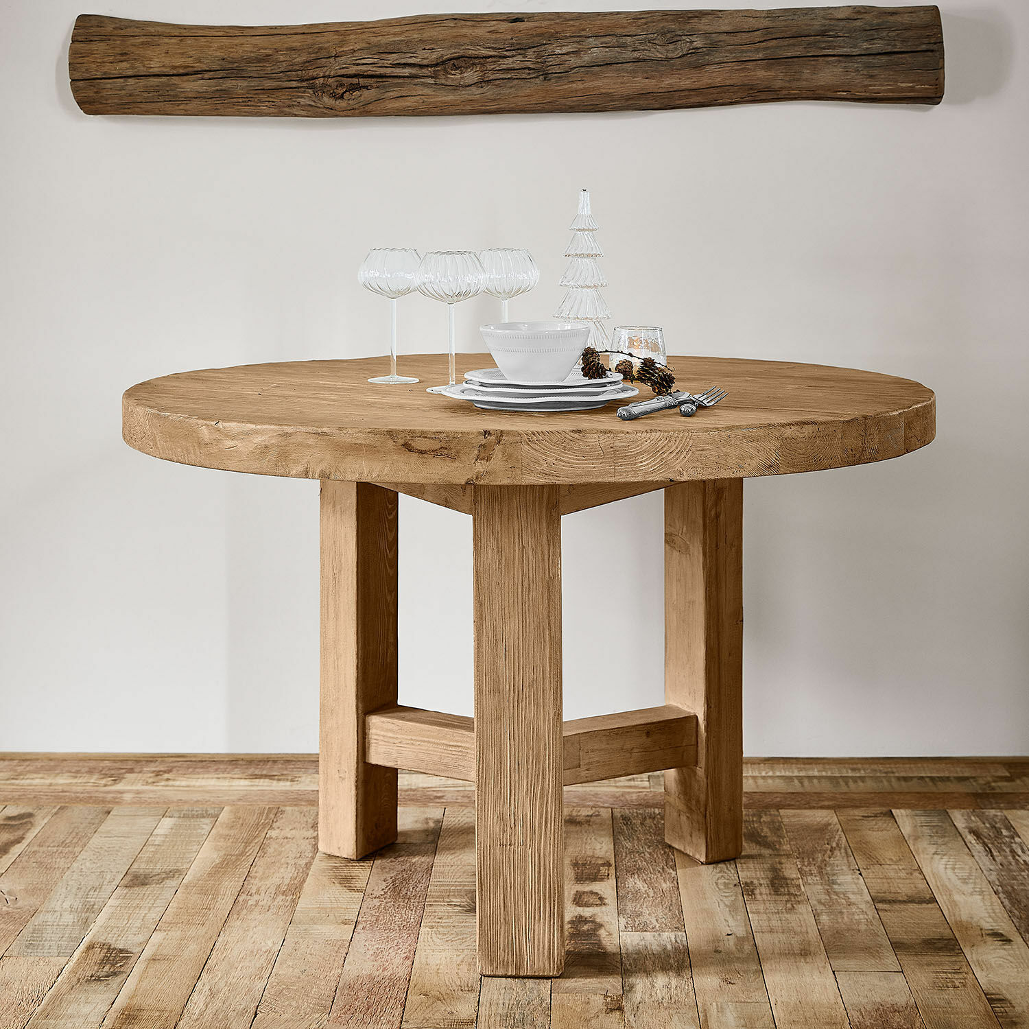 Runder Tisch aus massivem Holz in Naturfarbe mit Dekoration und Gläsern auf der Platte