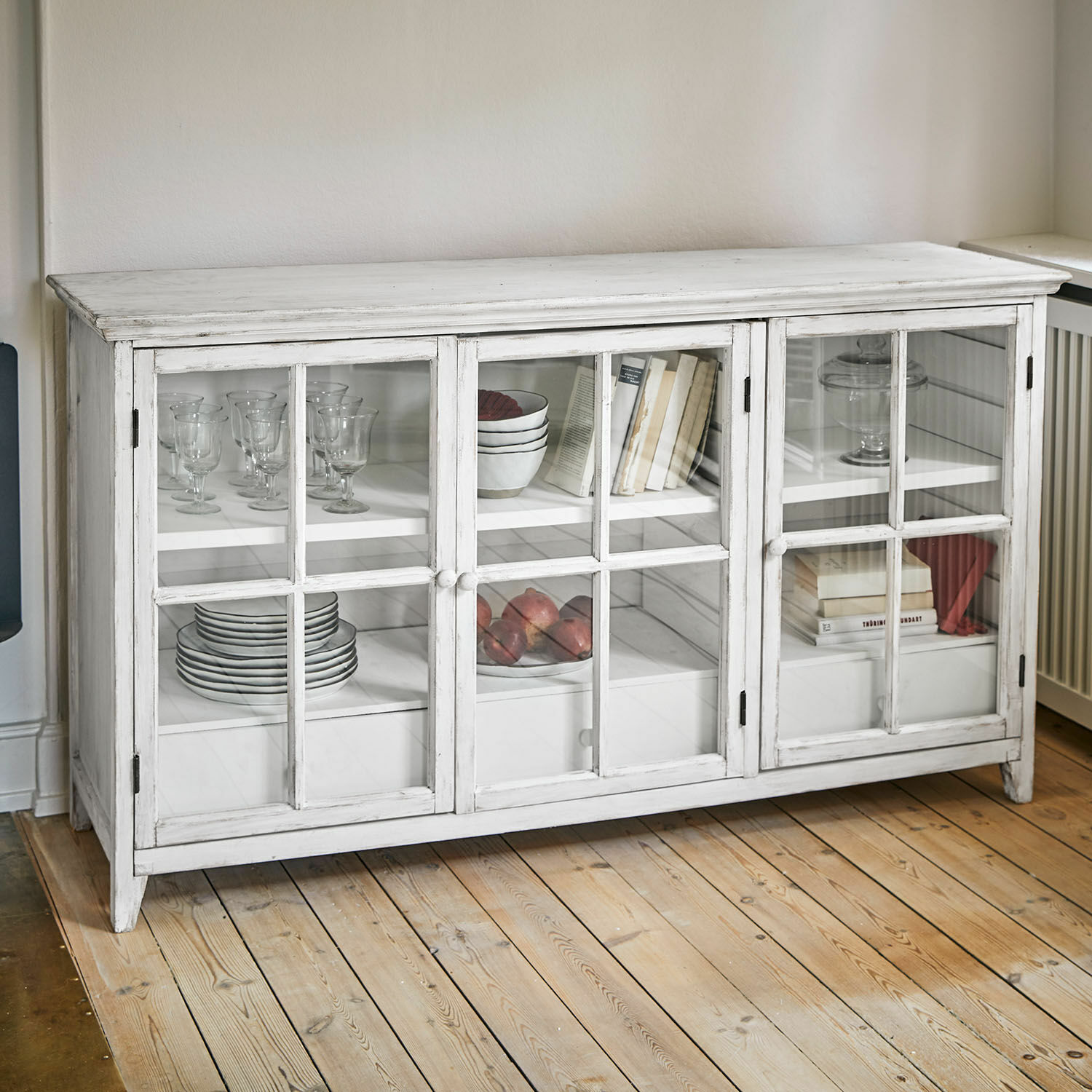 Weiße Holzvitrine mit Glastüren und Regalen für Geschirr und Bücher im Wohnzimmer