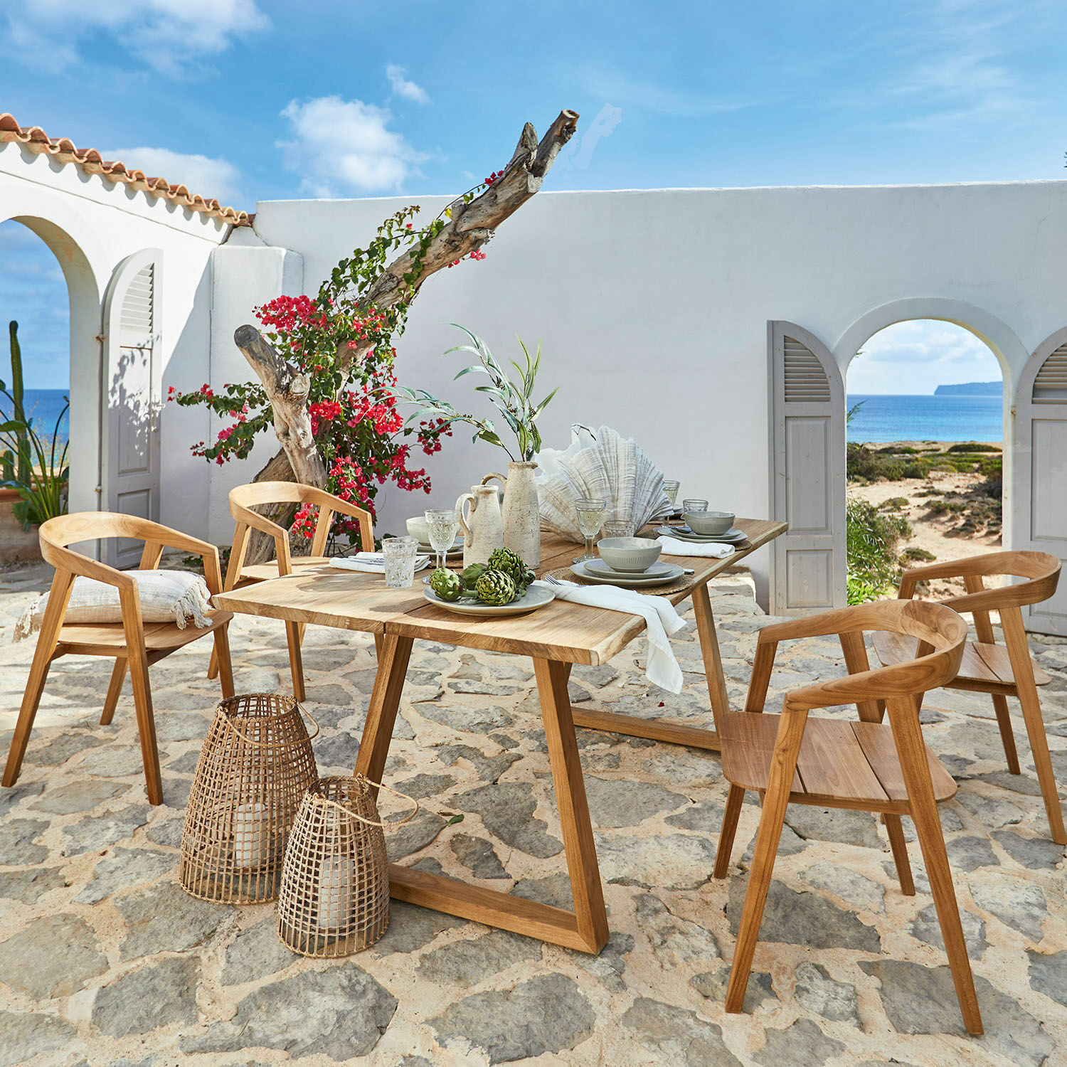 Tisch Saulny Gartenmöbel-Set aus Teakholz mit Stühlen und Tisch auf steinernem Patio mit Meerblick