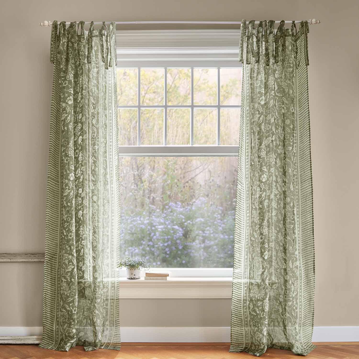 Grüne, transparente Vorhänge mit floralem Muster am Fenster, leichte Wohnraumdekoration aus Stoff.