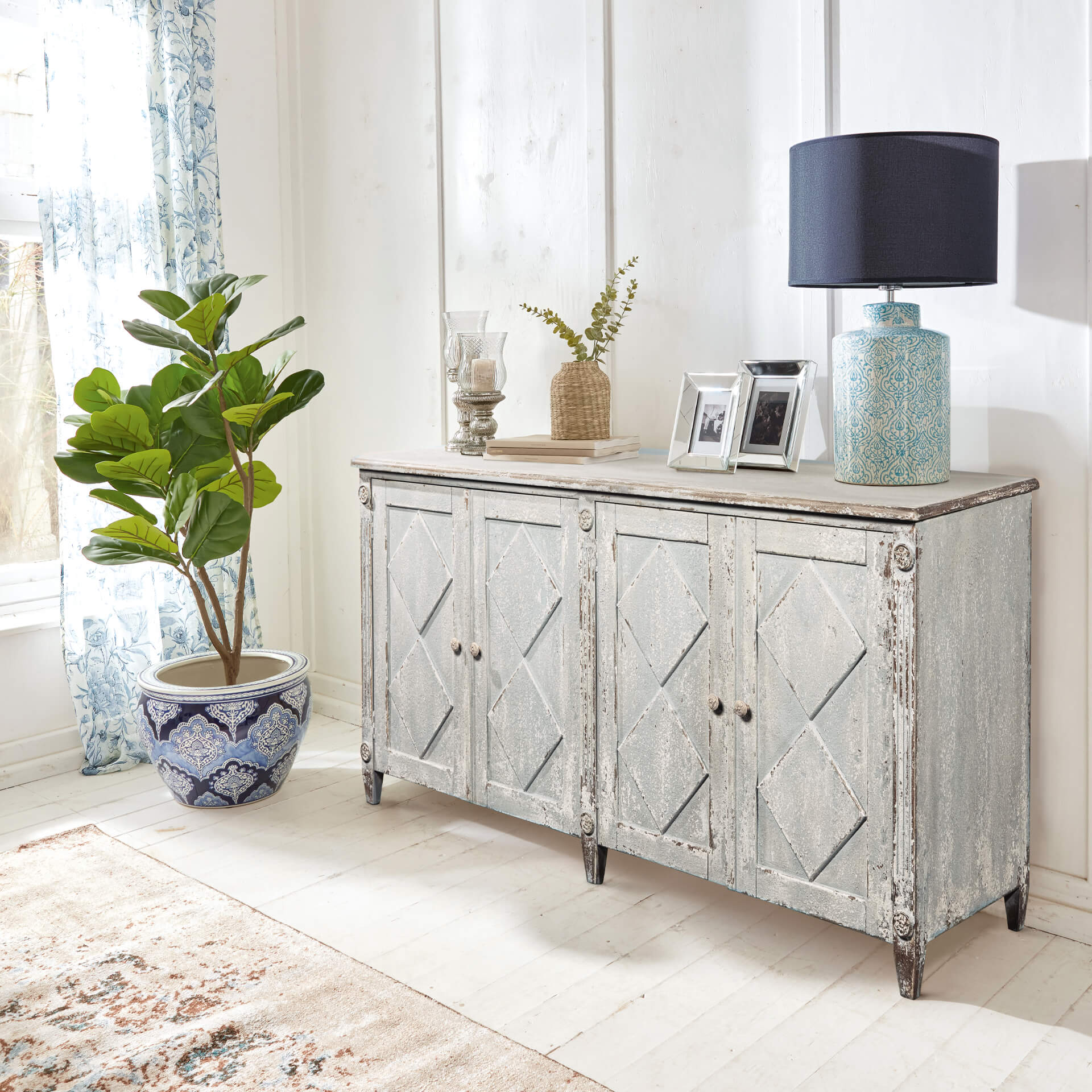 Vintage Holzkommode in Hellgrau mit dekorativen Türen und Wohnaccessoires darauf