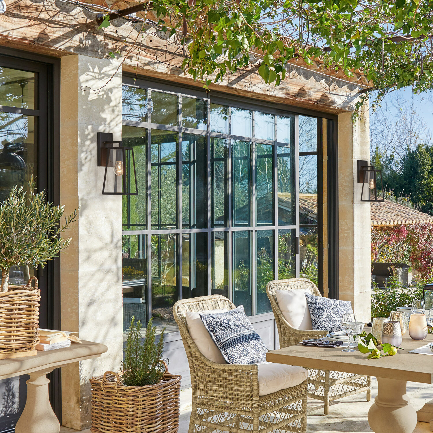Gemütliche Terrasse mit Rattanstühlen und beigen Kissen, natürliche Gartenmöbel im Freien