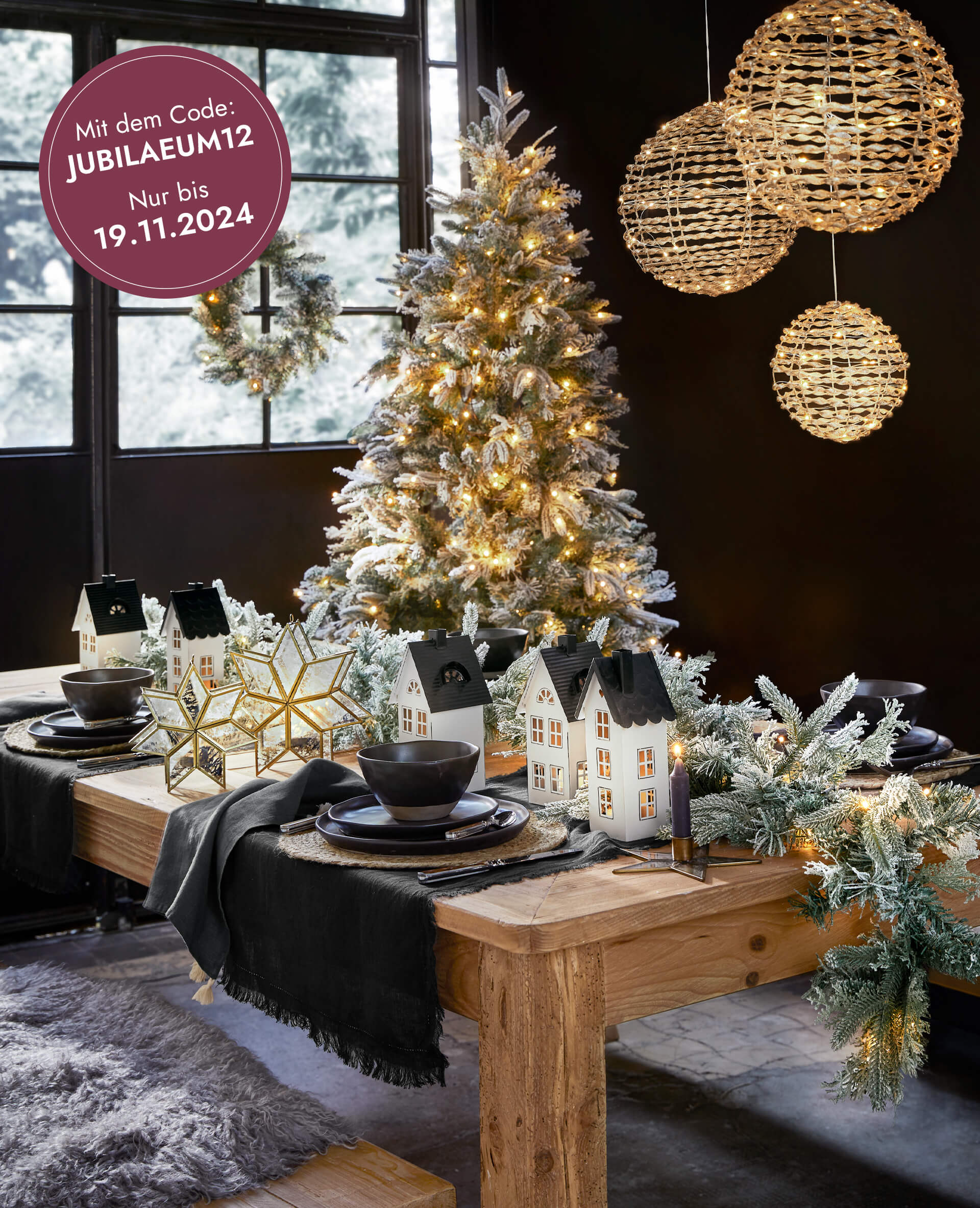 Weihnachtlich dekorierter Holztisch mit beleuchteten Häuschen, LED-Girlanden und geschmücktem Baum