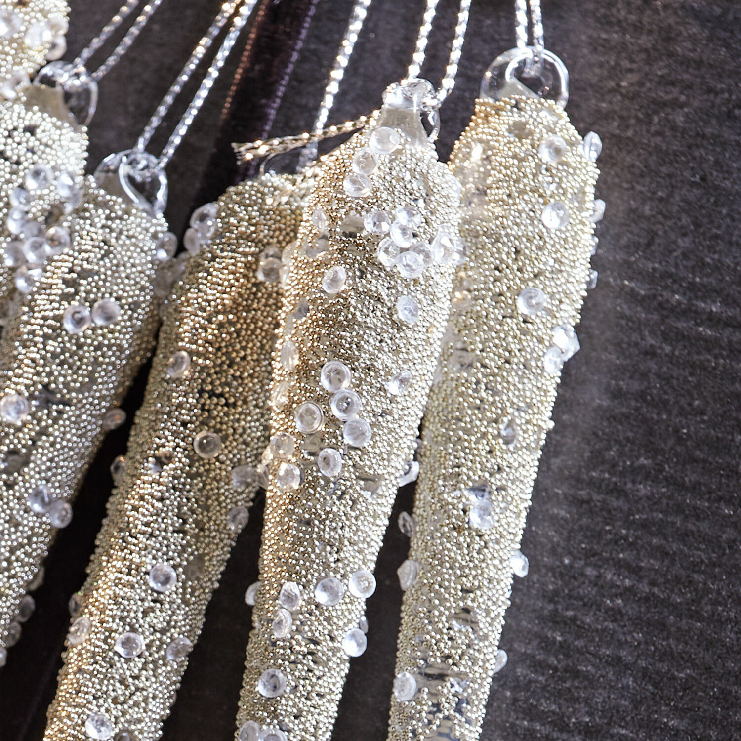 Goldene hängende Dekorationen mit kleinen Perlen und transparenten Kristallen auf dunklem Hintergrund