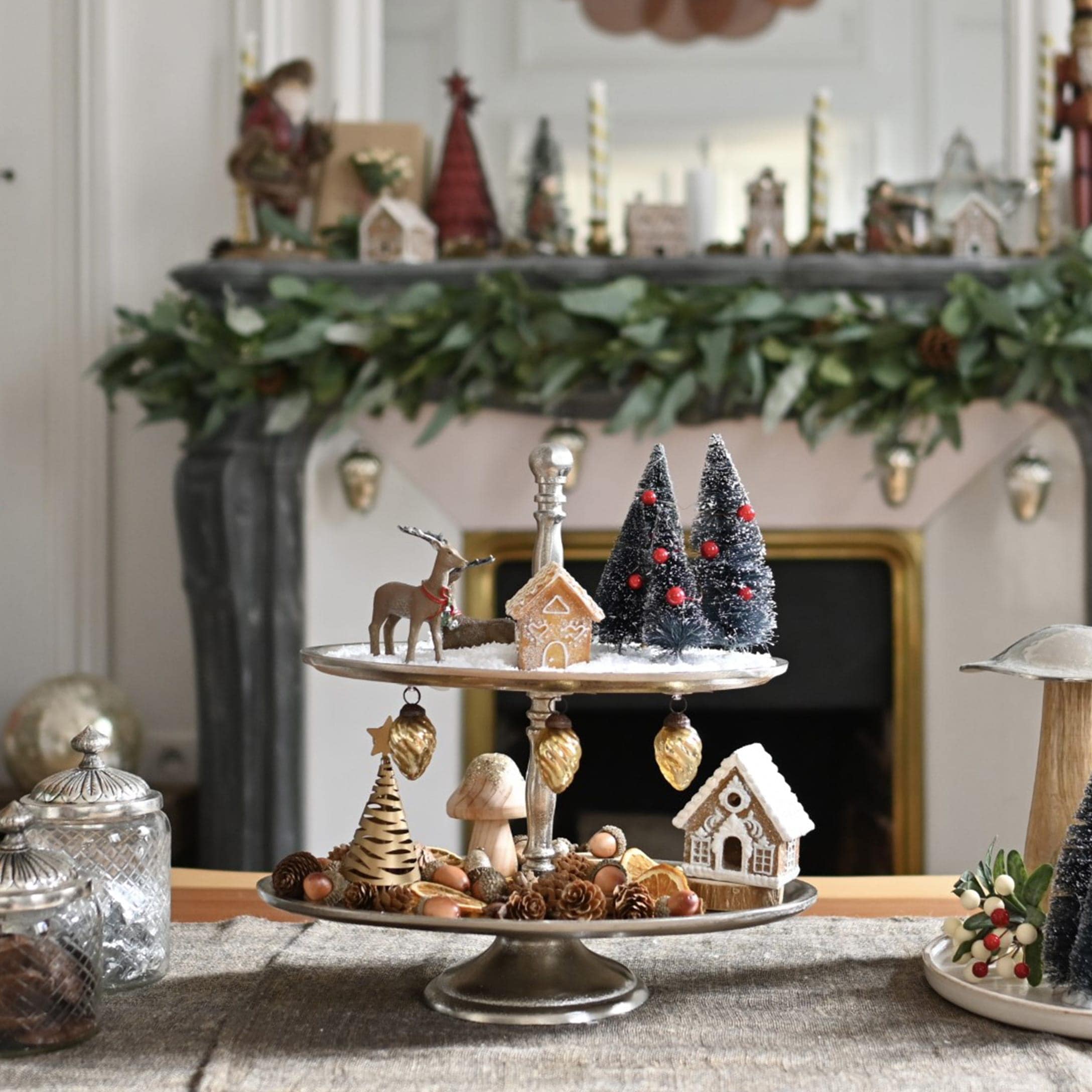 Zweistöckige Metall-Etagere mit Weihnachtsdekorationen und Lebkuchenhäusern auf Tisch