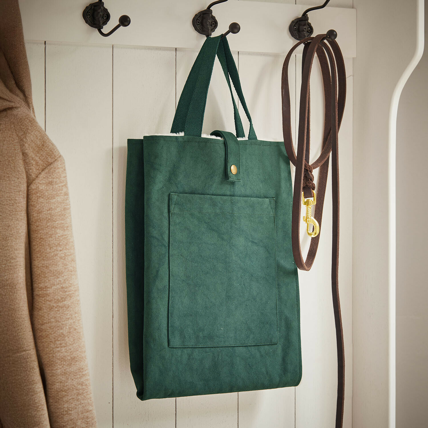 Haustiermatte Felliro Grüne Stofftasche an weißem Holzkleiderhaken neben brauner Leine und beigem Mantel