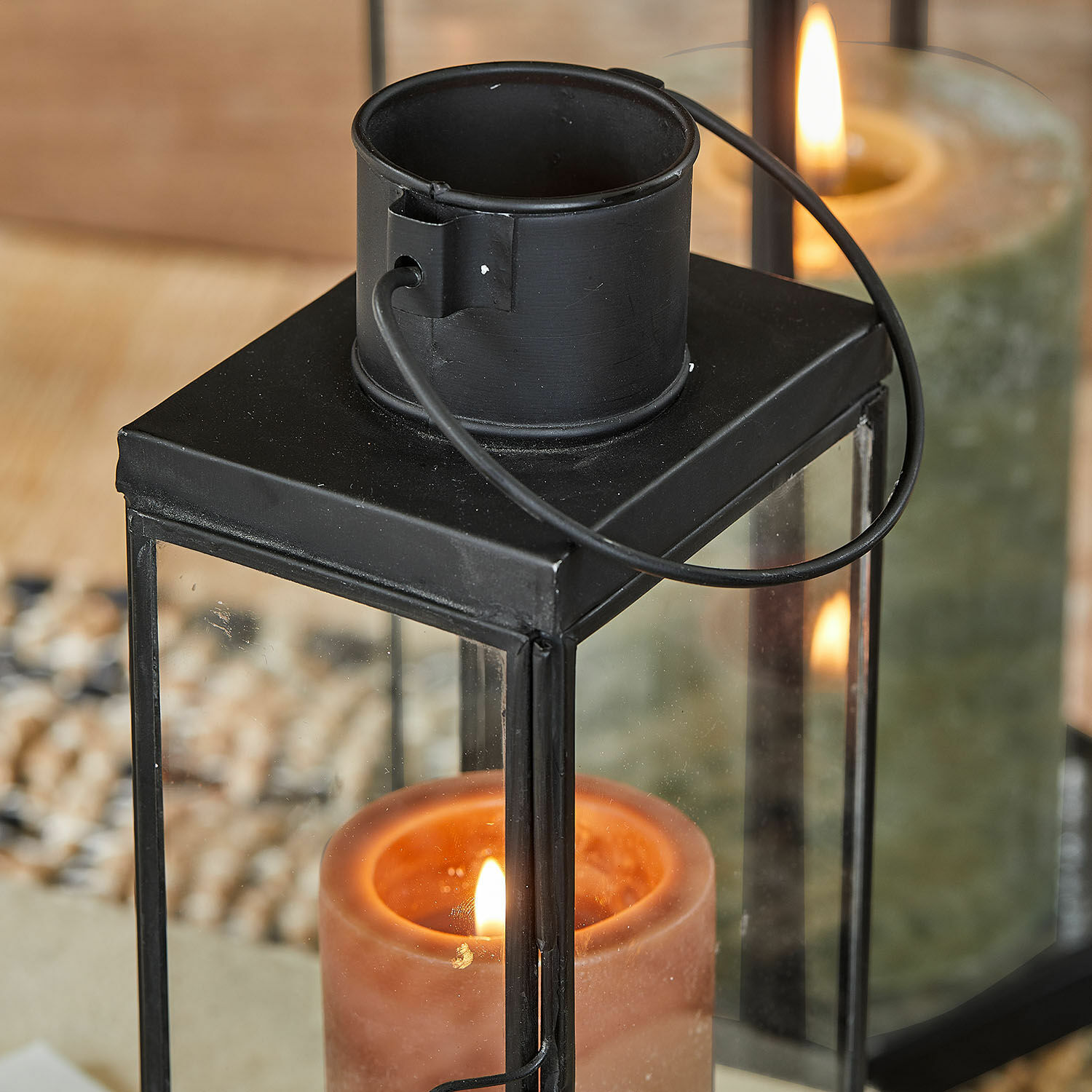 Schwarze Metalllaterne mit klarem Glas und brennender oranger Kerze innen, Wohnaccessoire