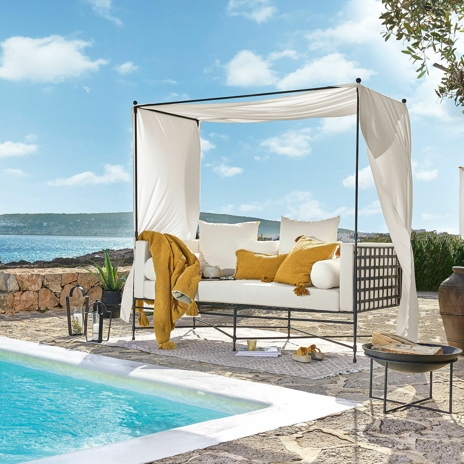 Weiße Metallsofa mit Baldachin und gelben Kissen am Pool auf steinerner Terrasse